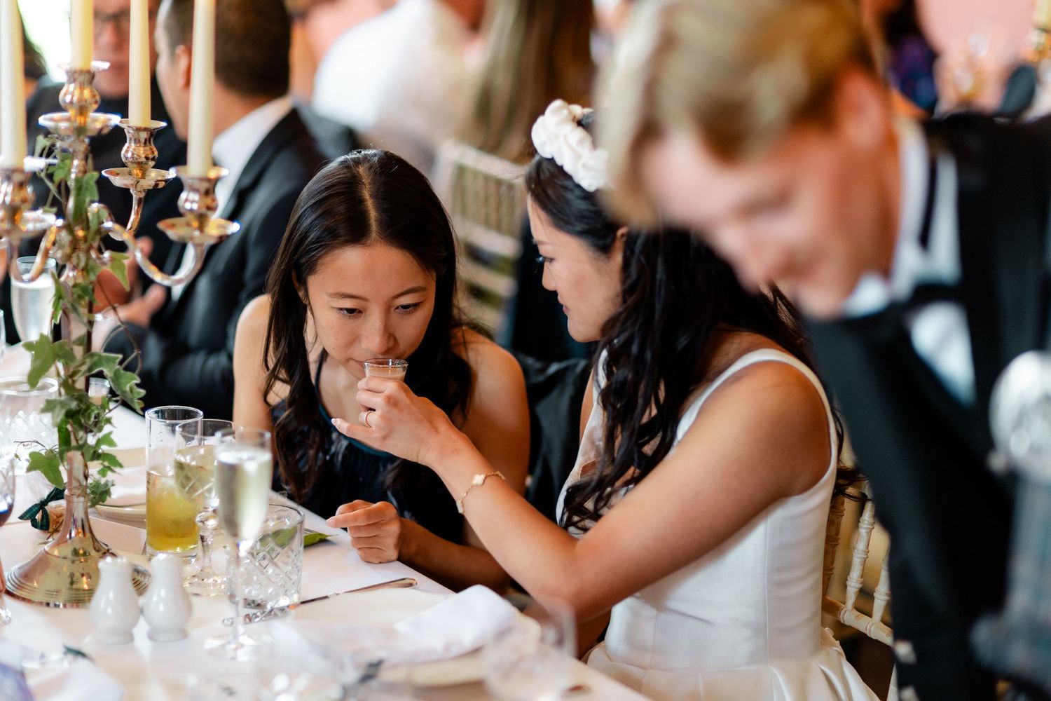 Wedding reception guests engaged in lively conversation around elegant dining tables.