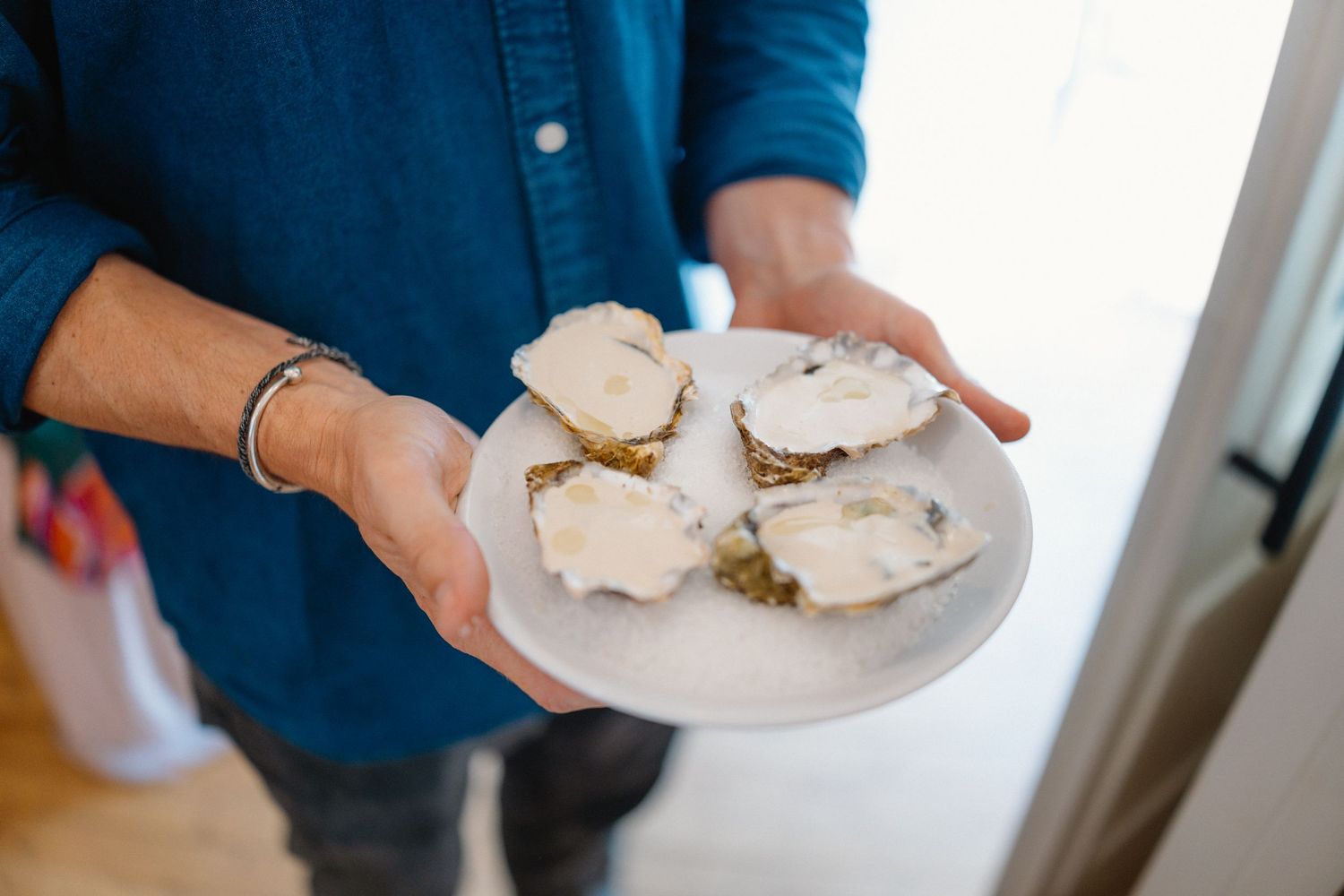Hands holding white plates with food at a catered event.