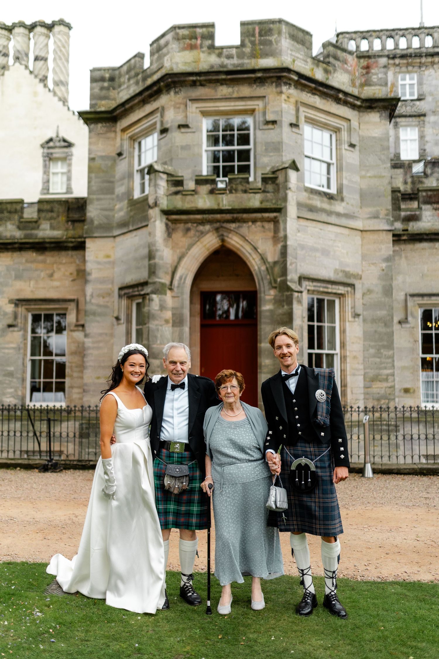 Wedding party portrait in front of Scottish castle architecture.