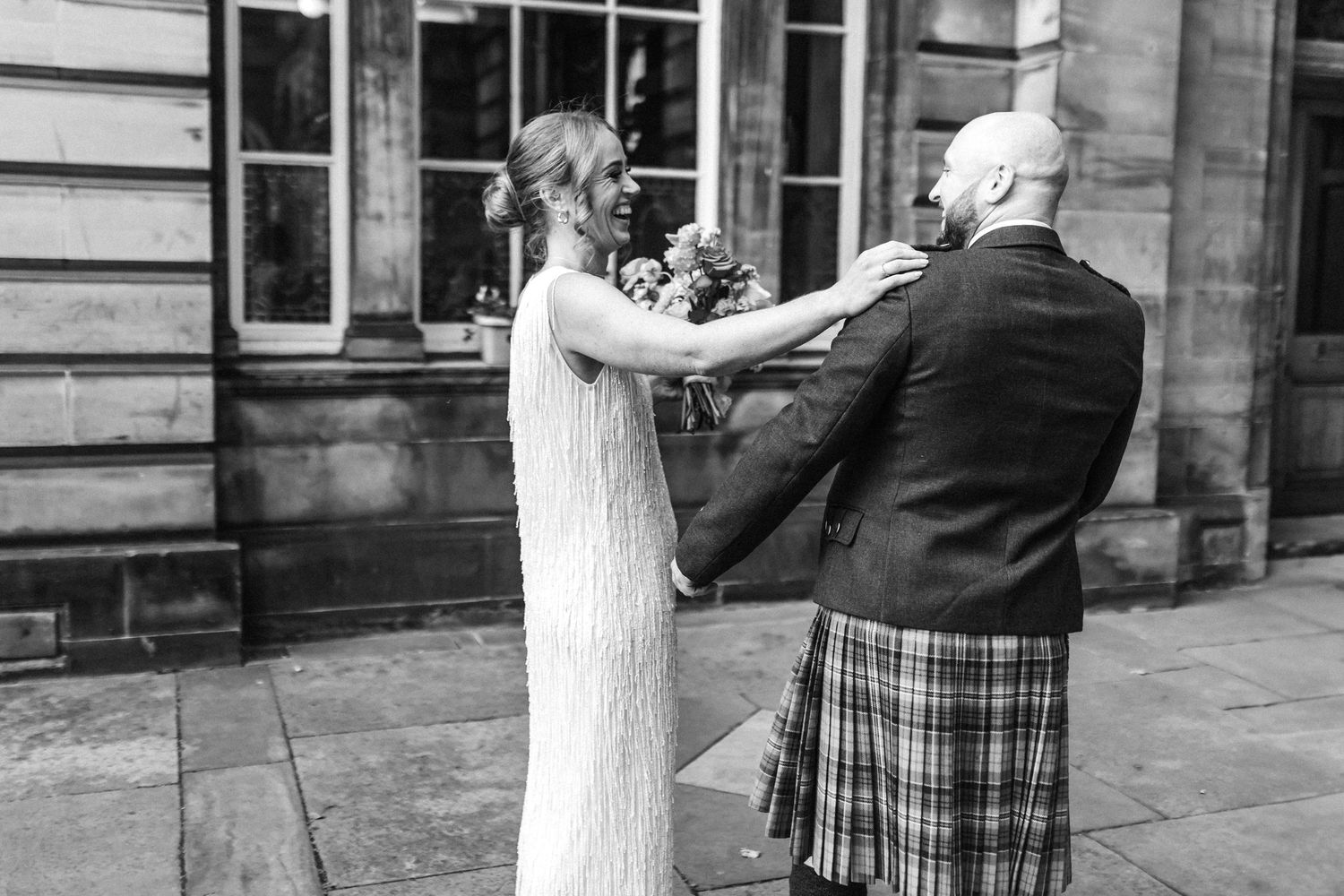 Couple sharing intimate moment in front of stone building during wedding celebration.