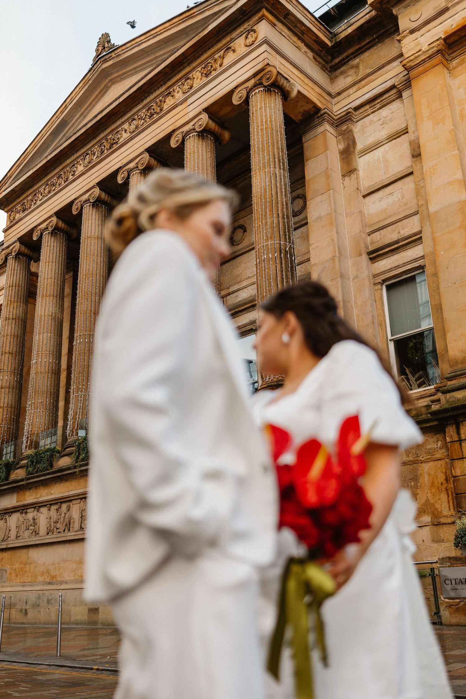 Classical architecture with grand columns forms backdrop for wedding photography.
