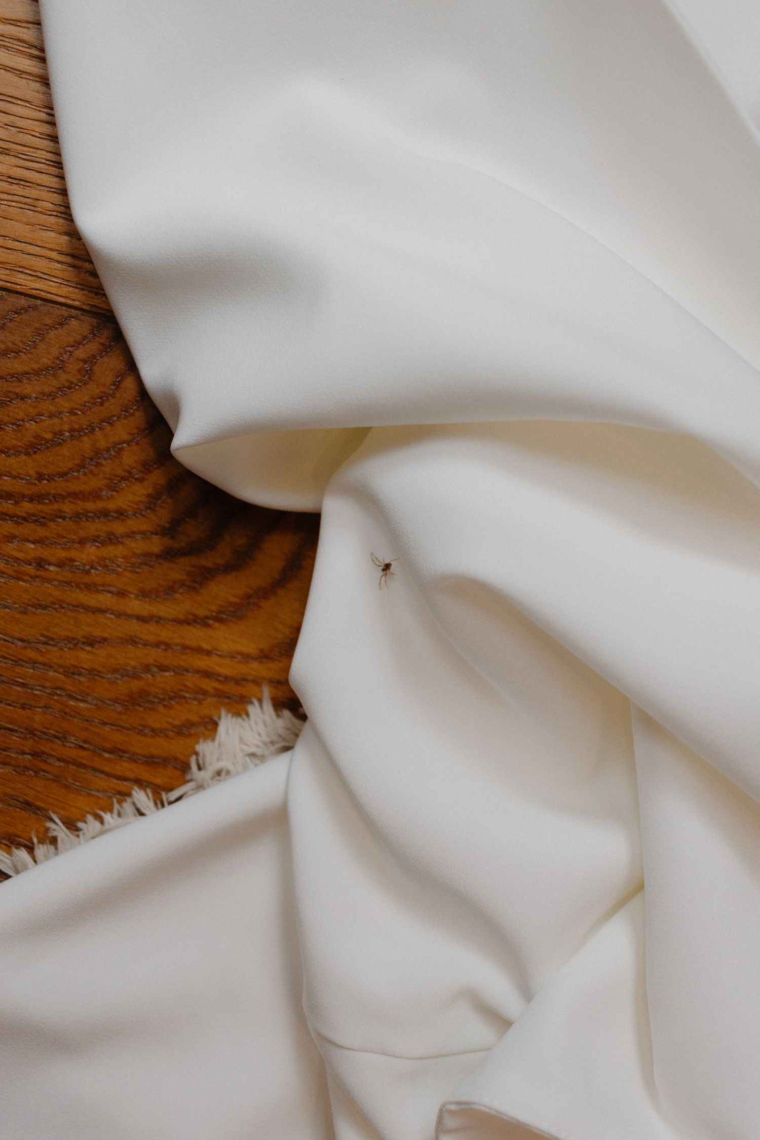 Elegant white bridal fabric draped over a wooden surface with soft natural lighting.