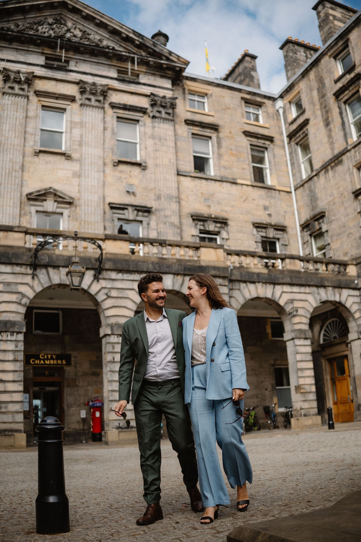A couple strolling together through a historic stone courtyard in Edinburgh.