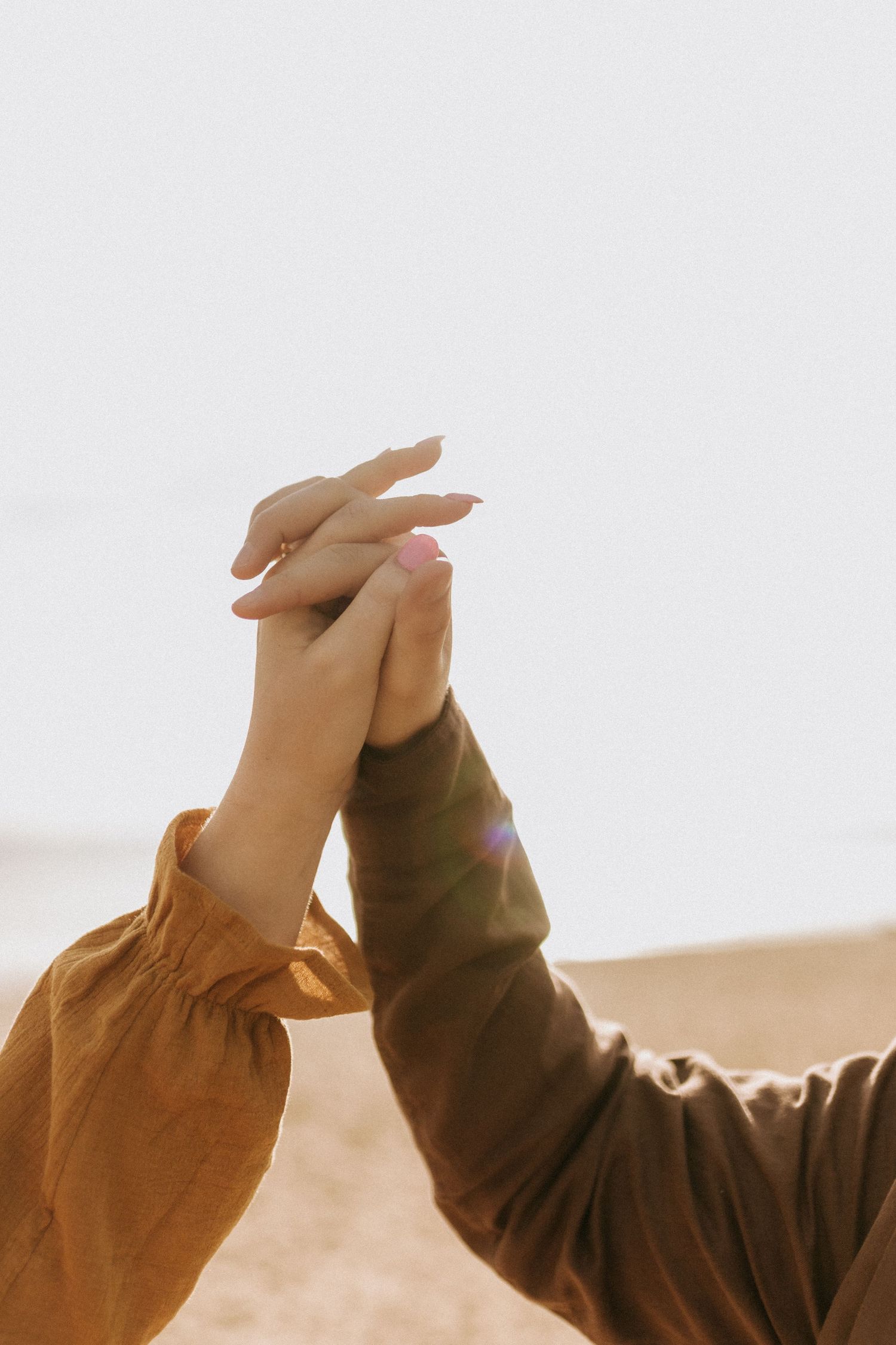 Two hands join together against a bright white background in an artistic pose.