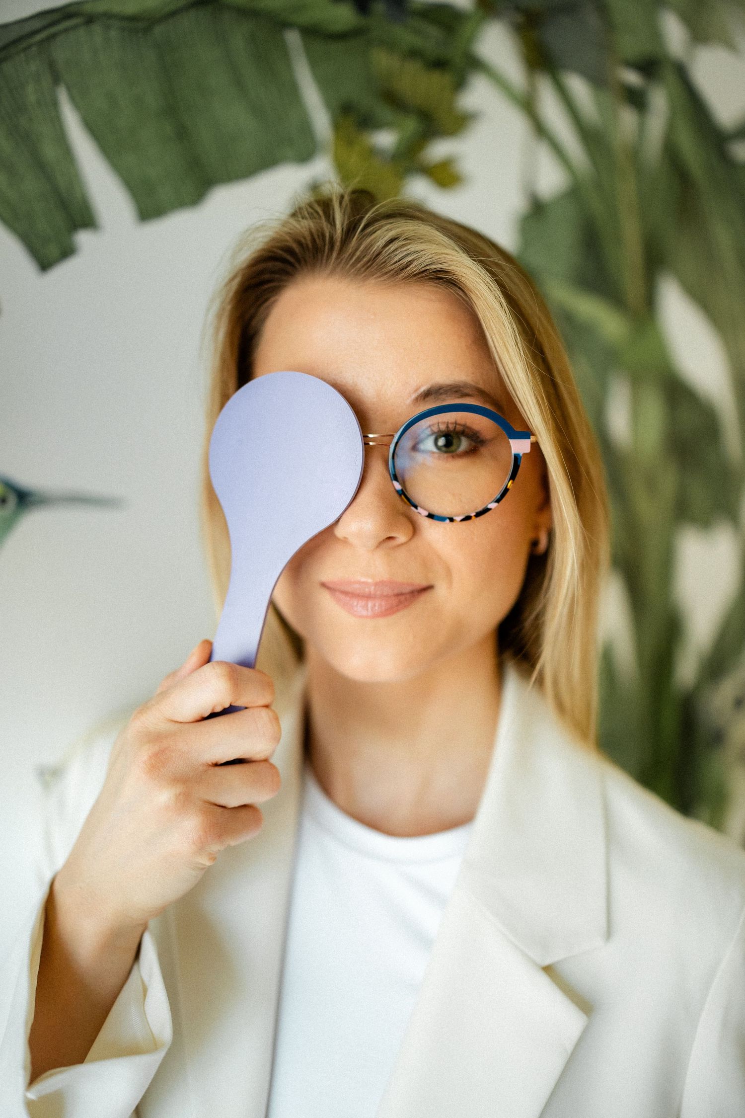 Creative portrait series with person in white holding paper against eye.