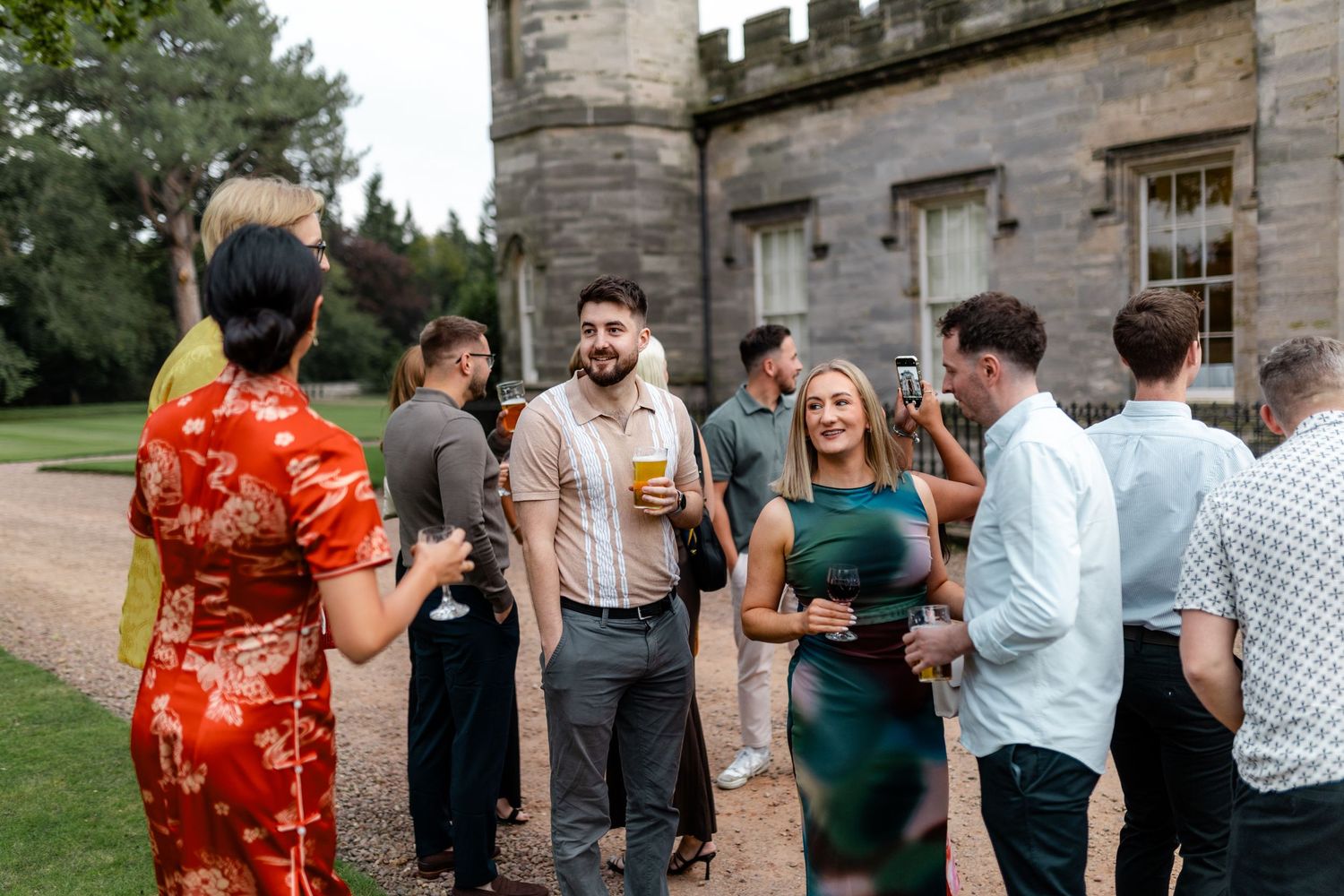 People socializing on the grounds of a historic mansion during an outdoor event.