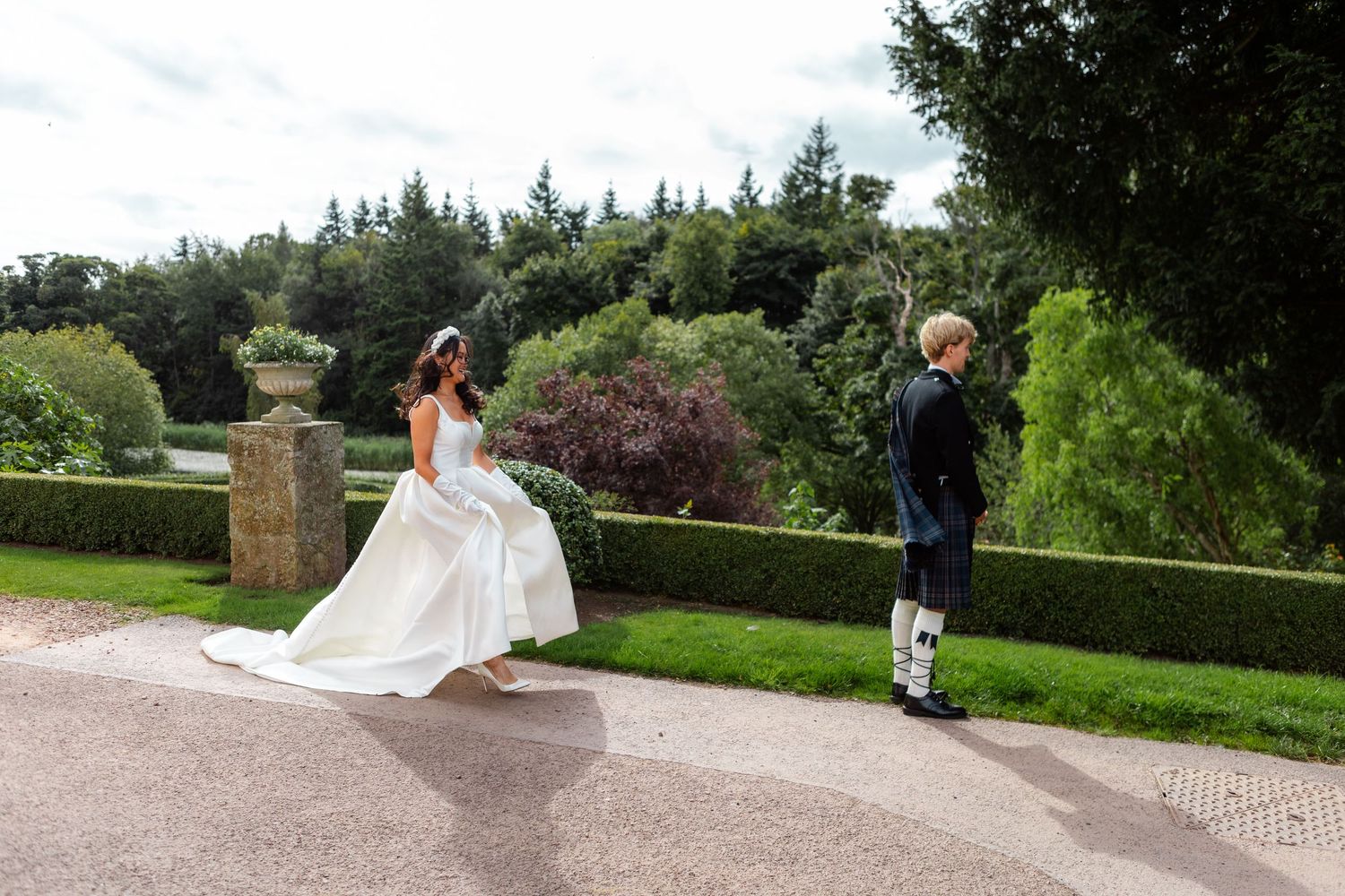 Wedding celebration in a formal garden setting with stone pathways and greenery.