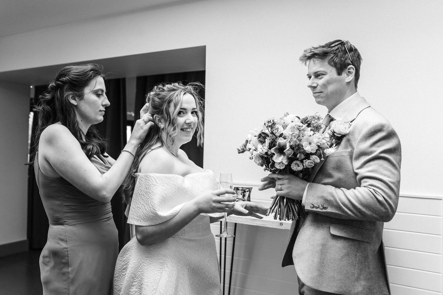 Wedding party members sharing drinks and conversation in a bright indoor space.