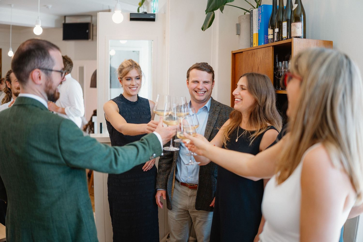 People mingling and socializing at an indoor event with bright natural lighting.