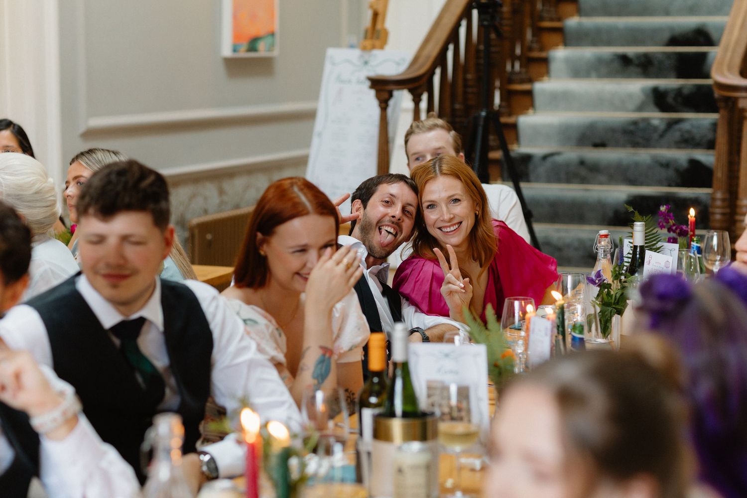 Bride and groom sharing a joyful moment with guests at elegant wedding reception dinner with candlelit tables.