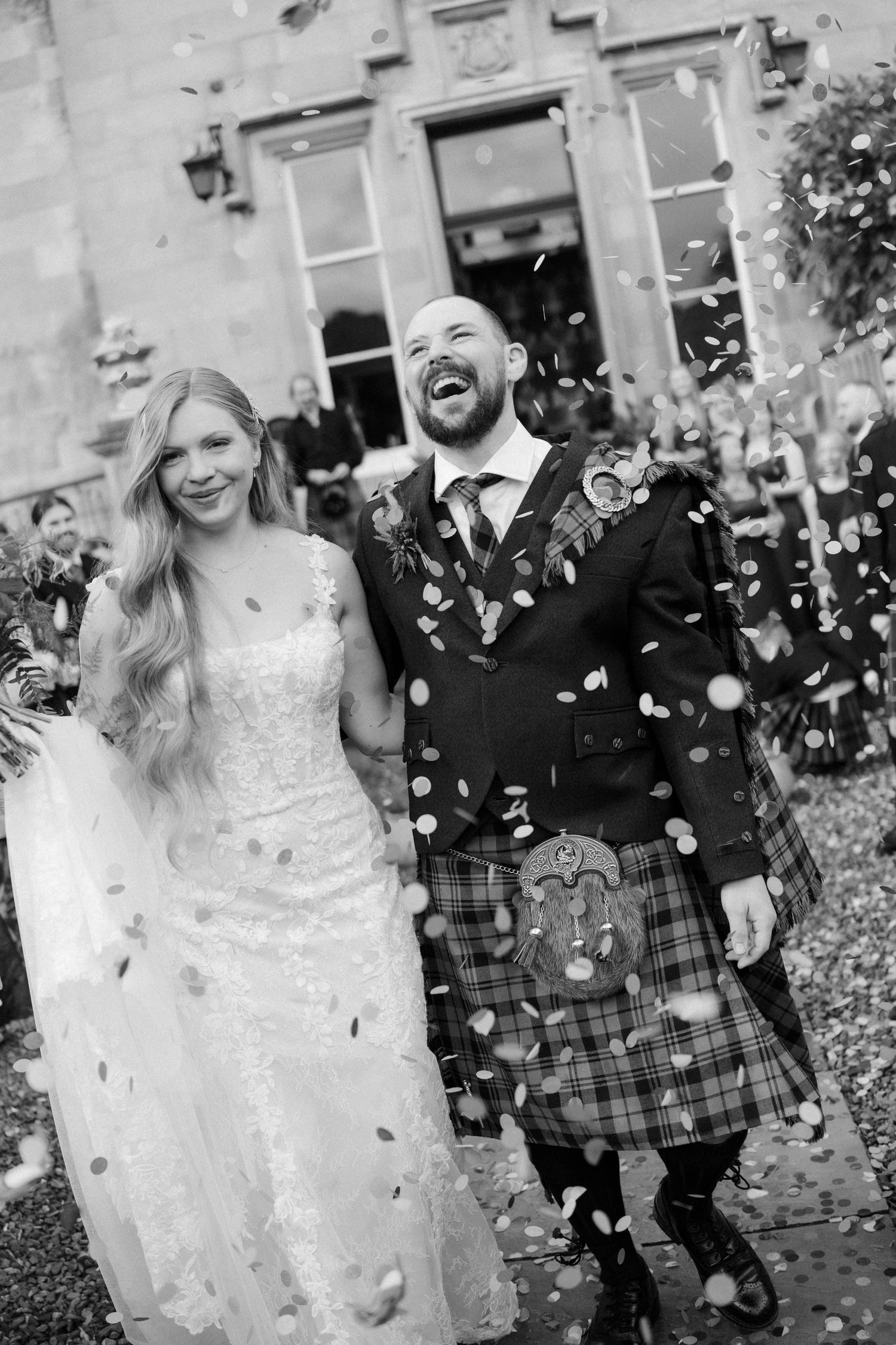 Newlyweds celebrating with confetti outside a stone building.