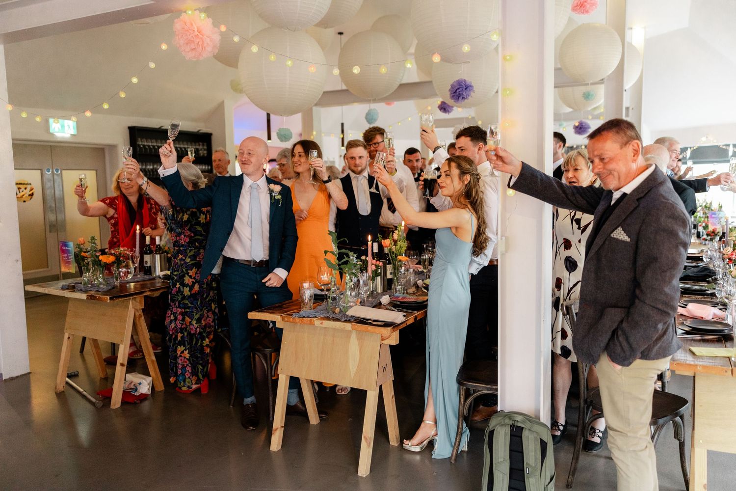 Wedding reception venue decorated with string lights and filled with guests celebrating at tables.