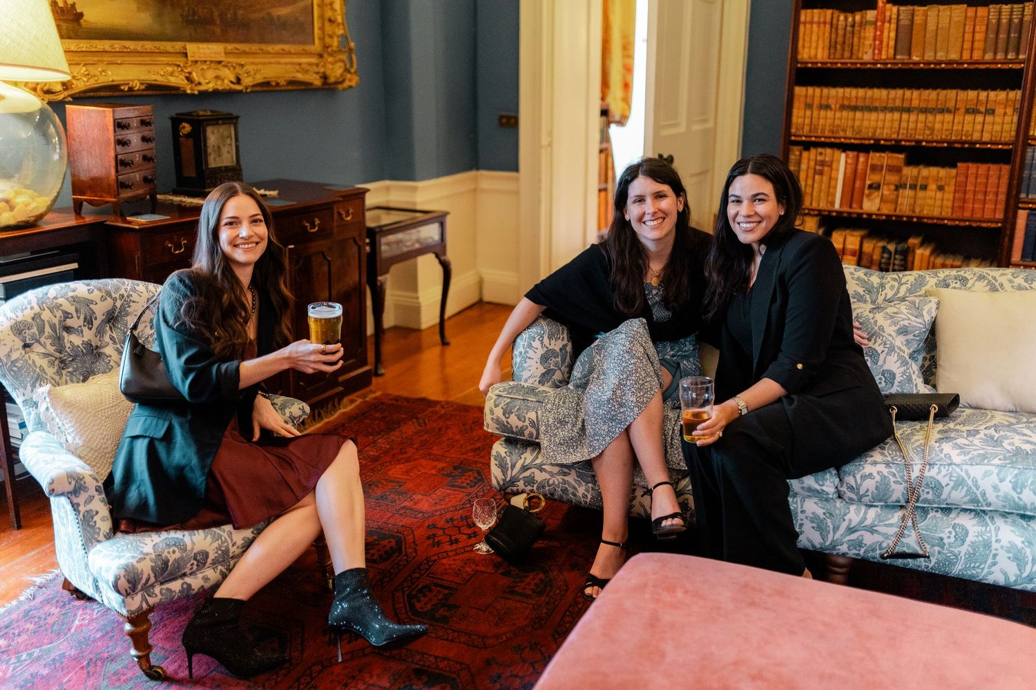 Guests relaxing on vintage furniture in a classic library setting.