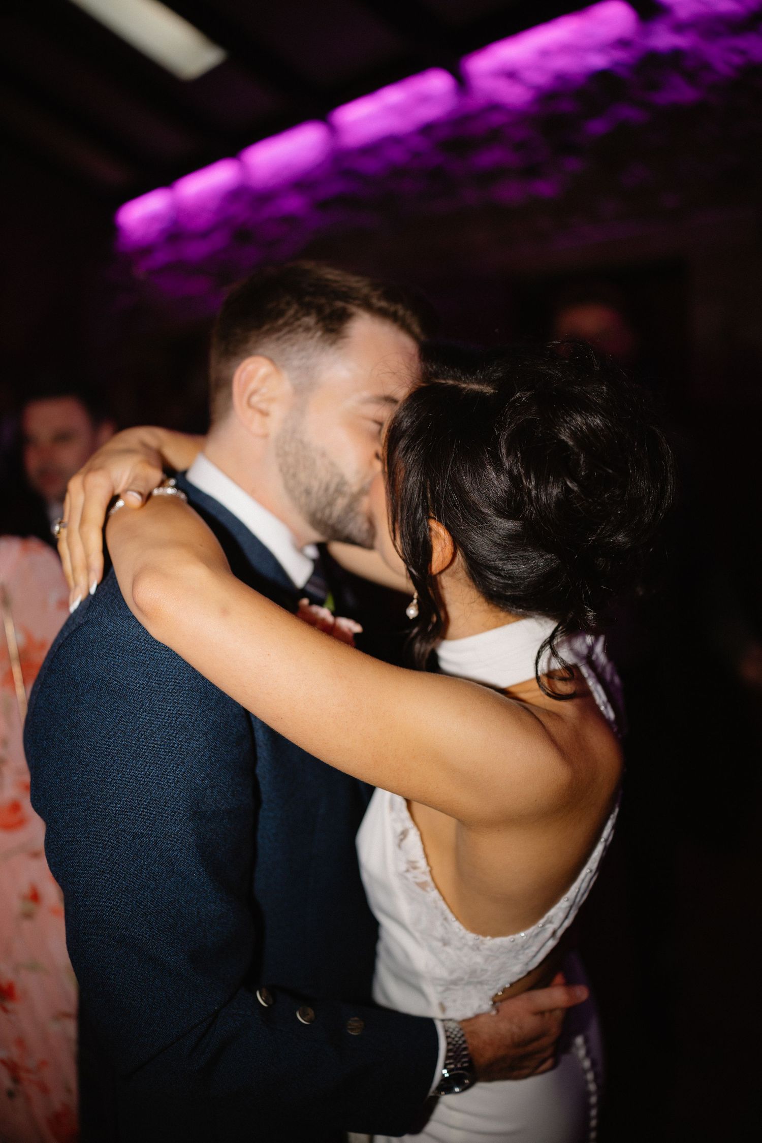 Bride and groom sharing a romantic kiss on the dance floor during their first dance at a wedding.
