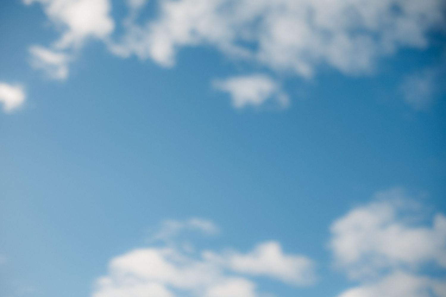 Fluffy white clouds float in a bright blue summer sky.