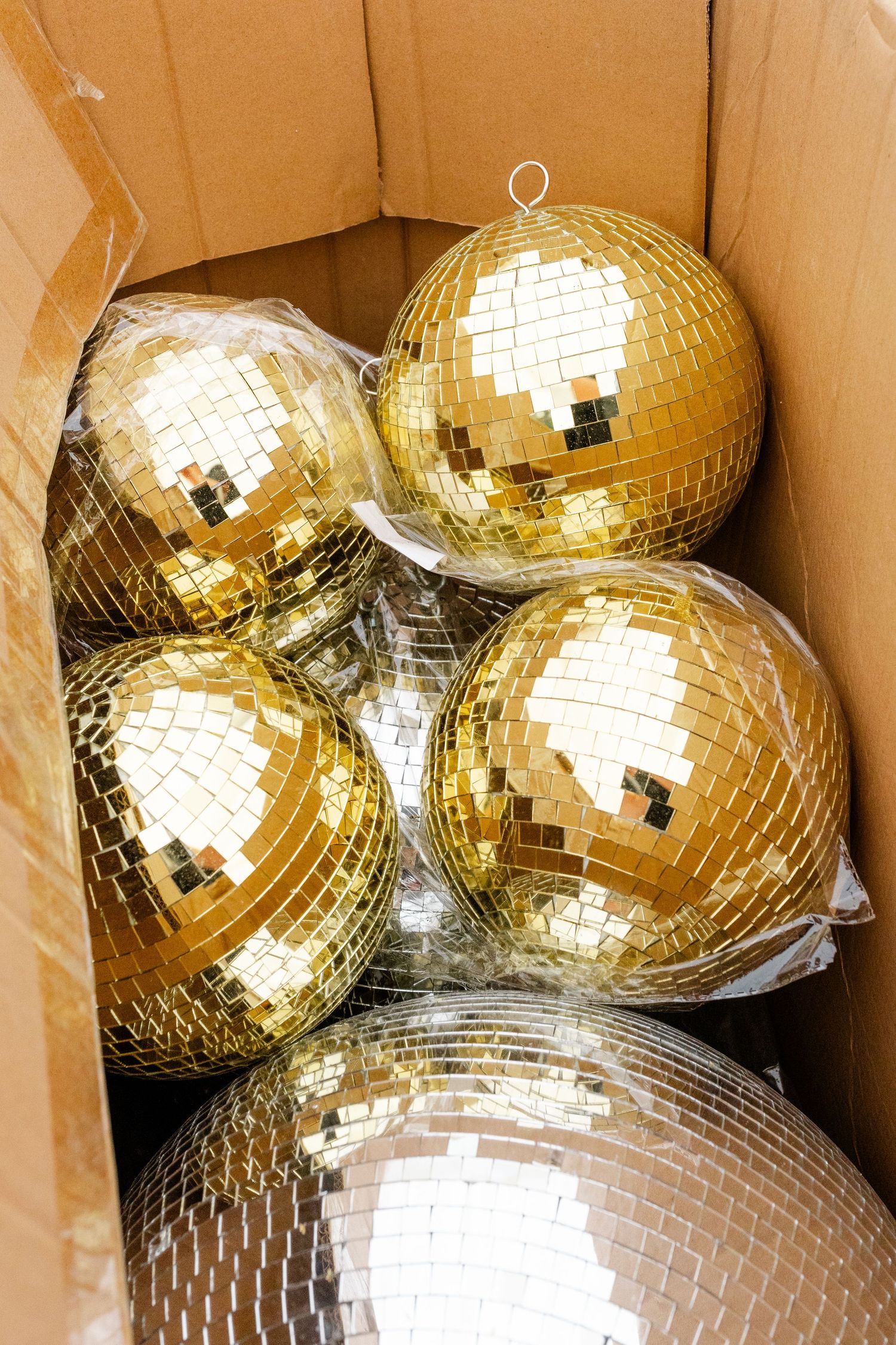 Collection of golden disco balls packed together in a cardboard box.