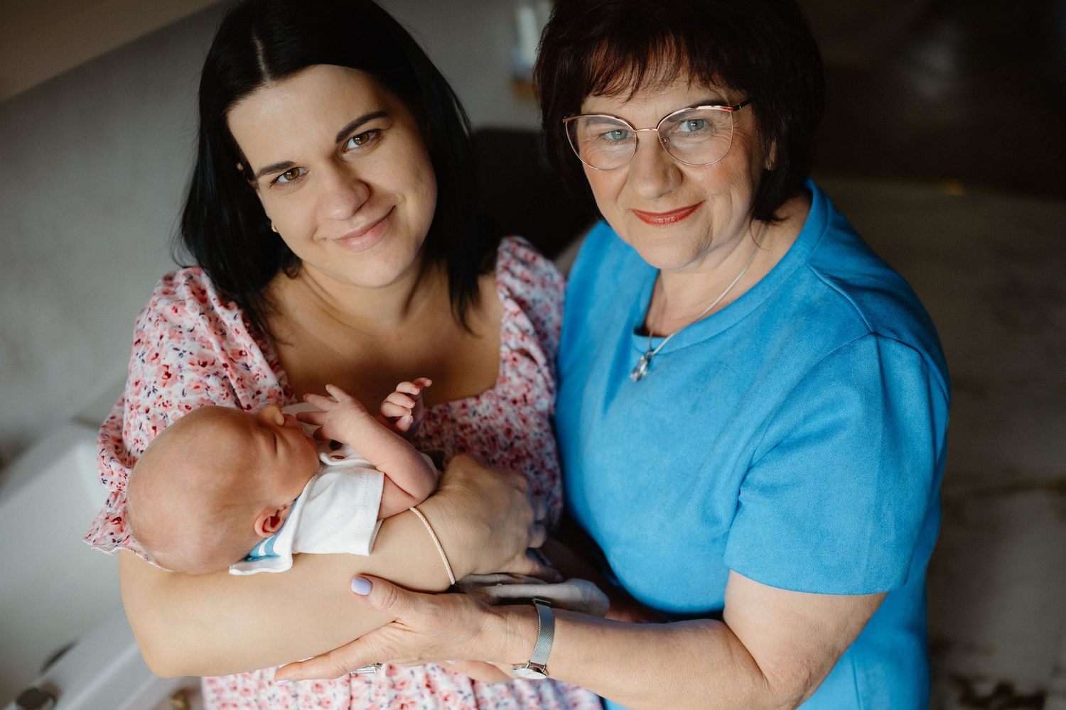 Family members sharing tender moments with a baby in casual home setting.