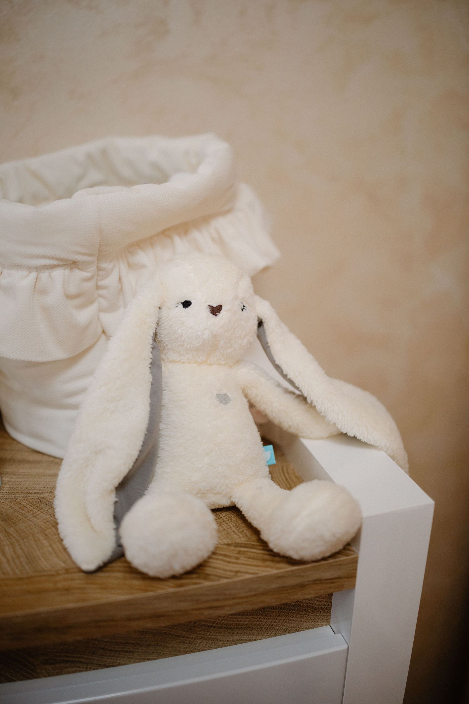 White plush stuffed animals arranged on wooden shelf for nursery decor.