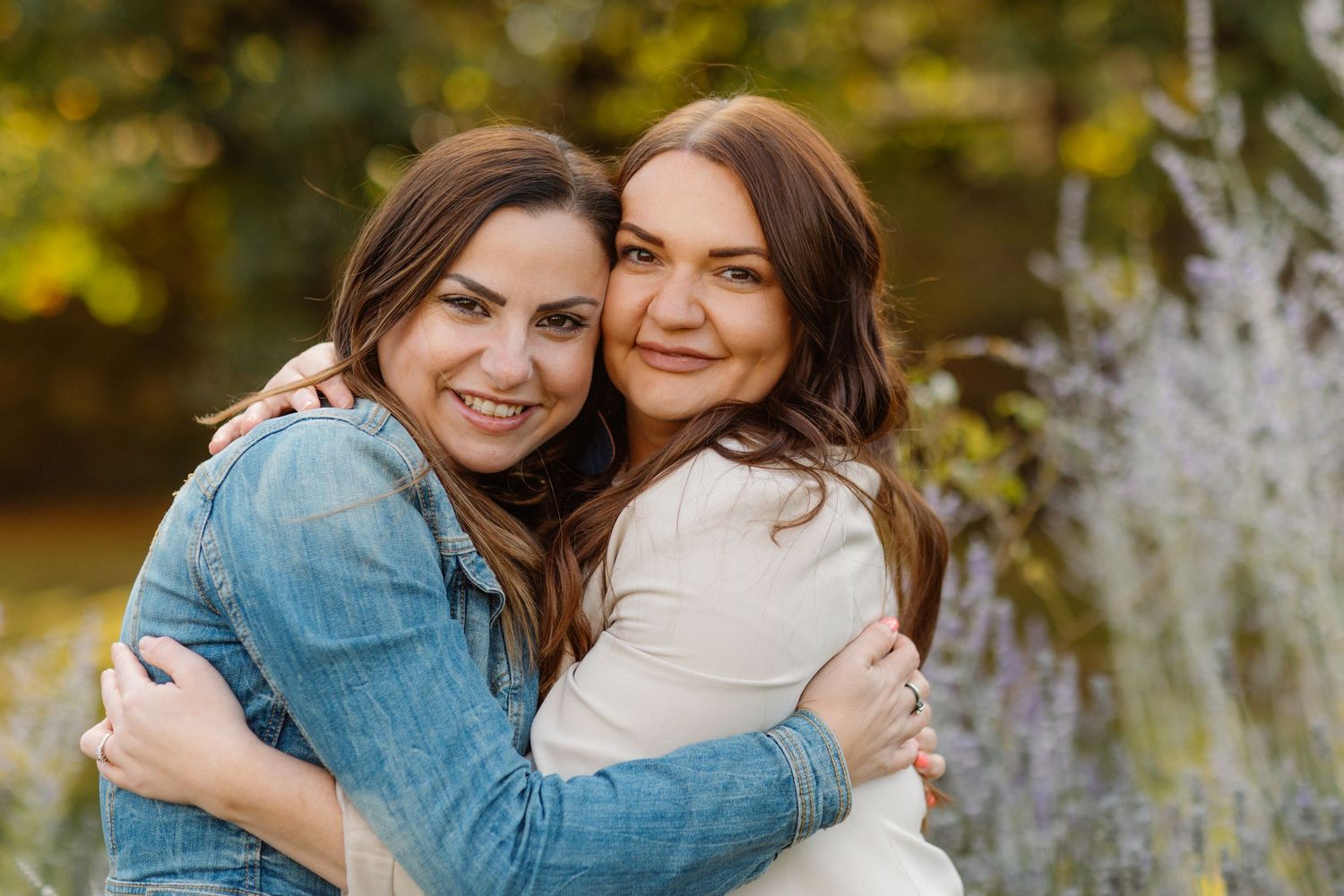 Two friends sharing a warm embrace and smiling outdoors.