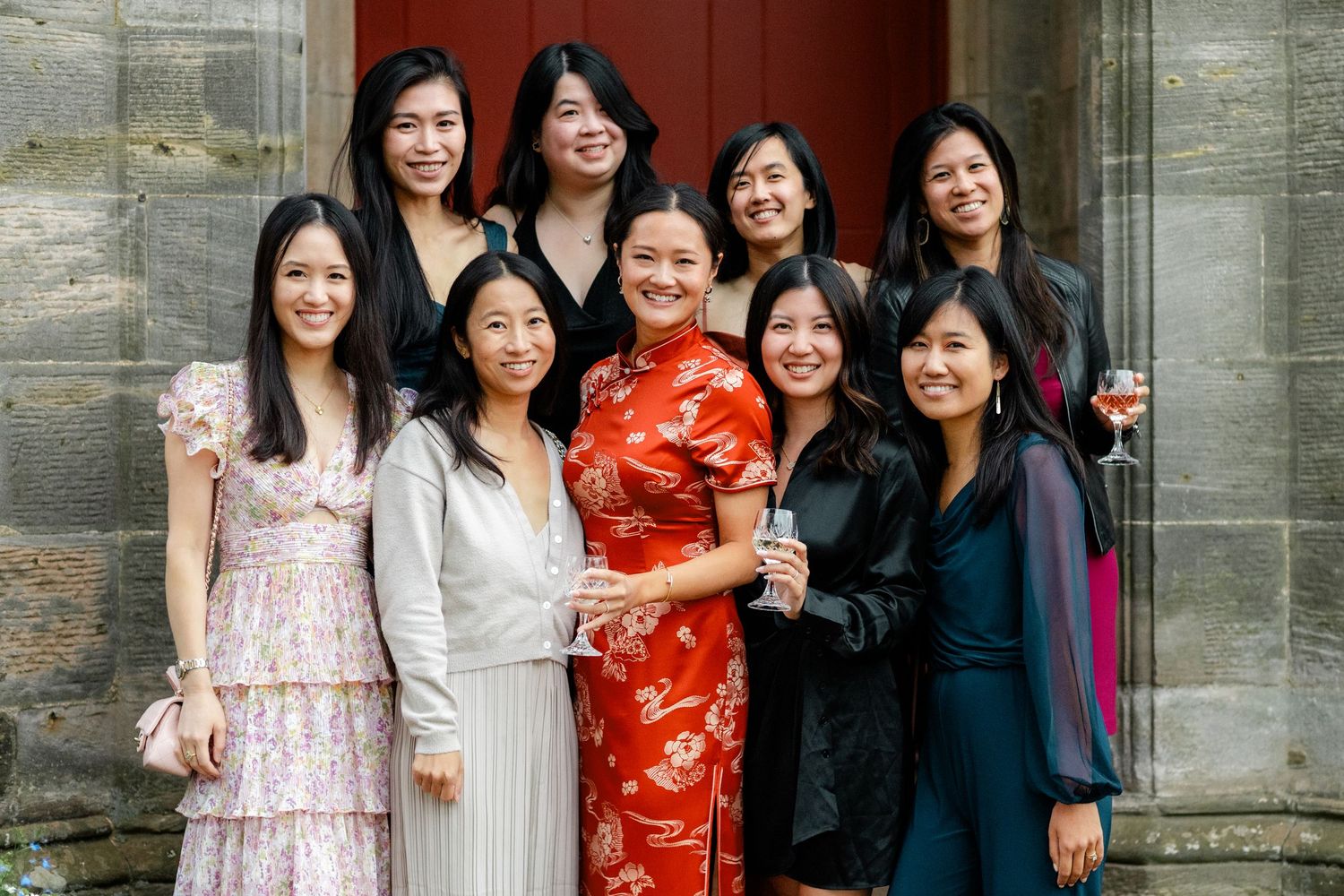 Friends gather for a festive photo outside a historic stone building entrance.
