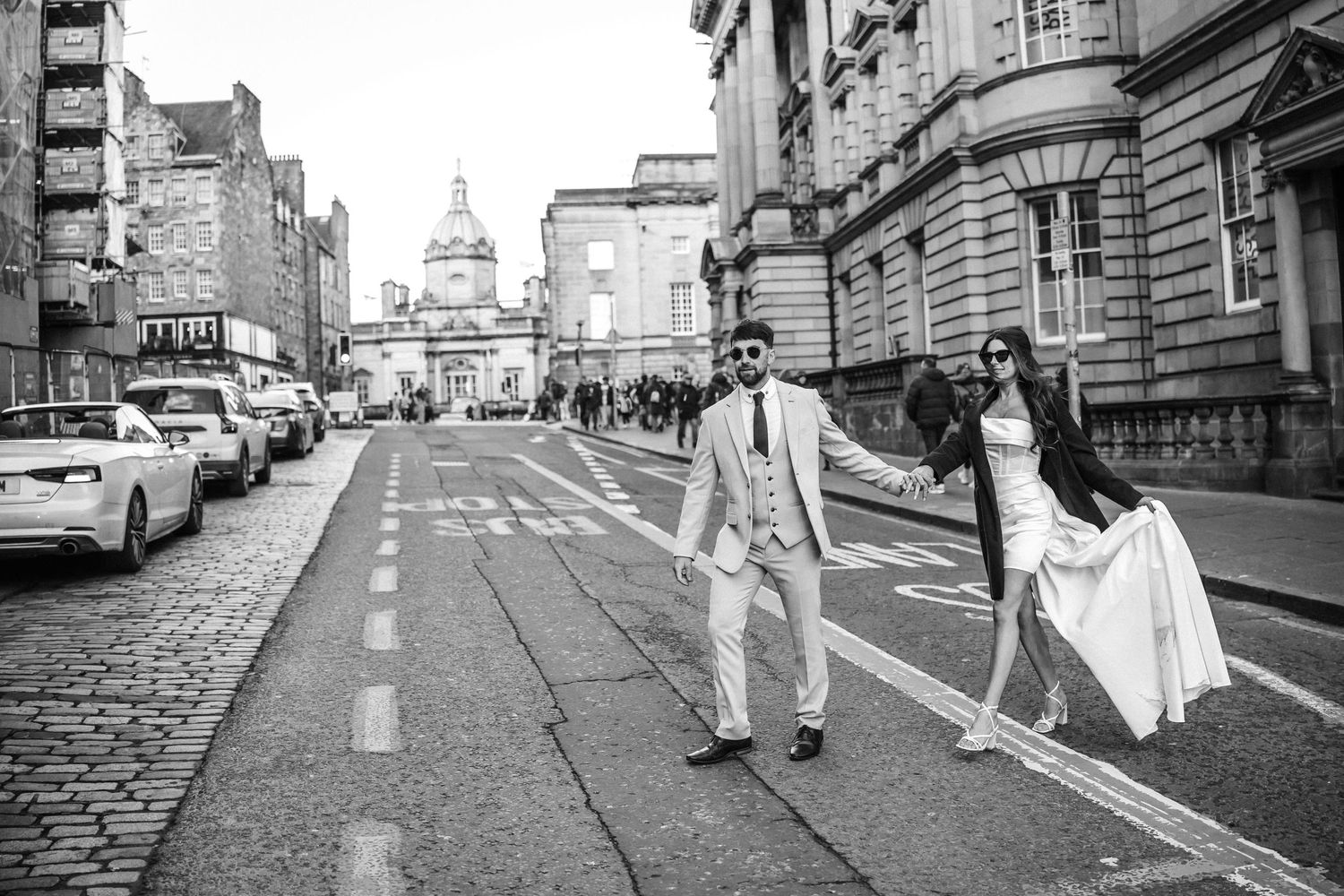 Black and white photos of people walking along a historic city street with classic architecture.