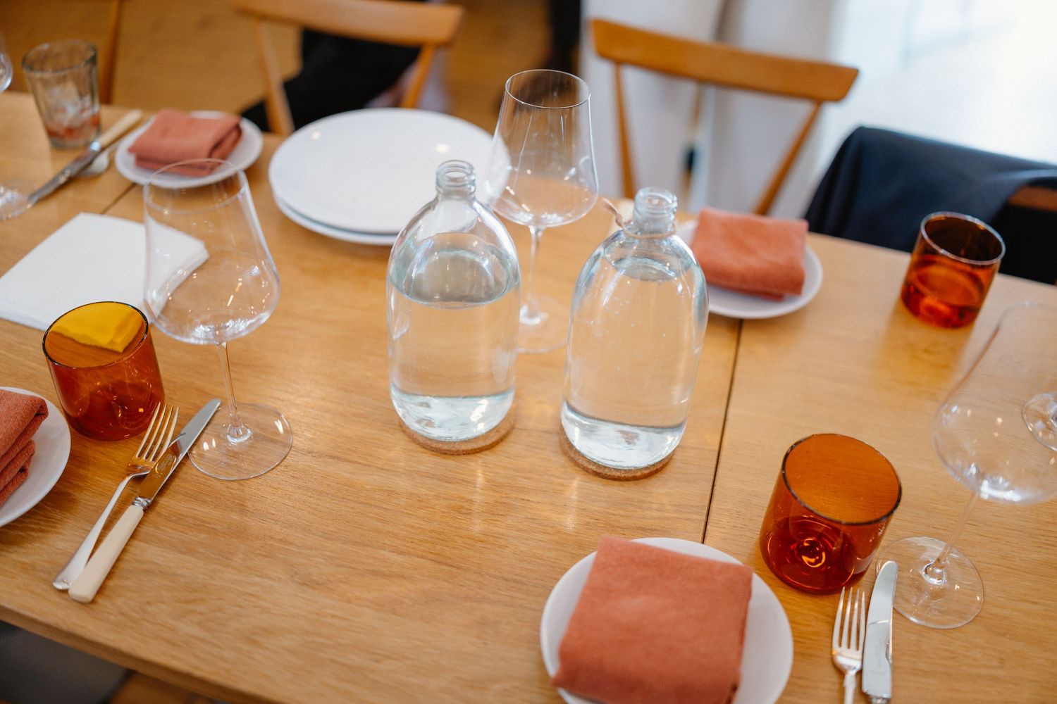 Place settings and glasses arranged on a wooden table at a restaurant.