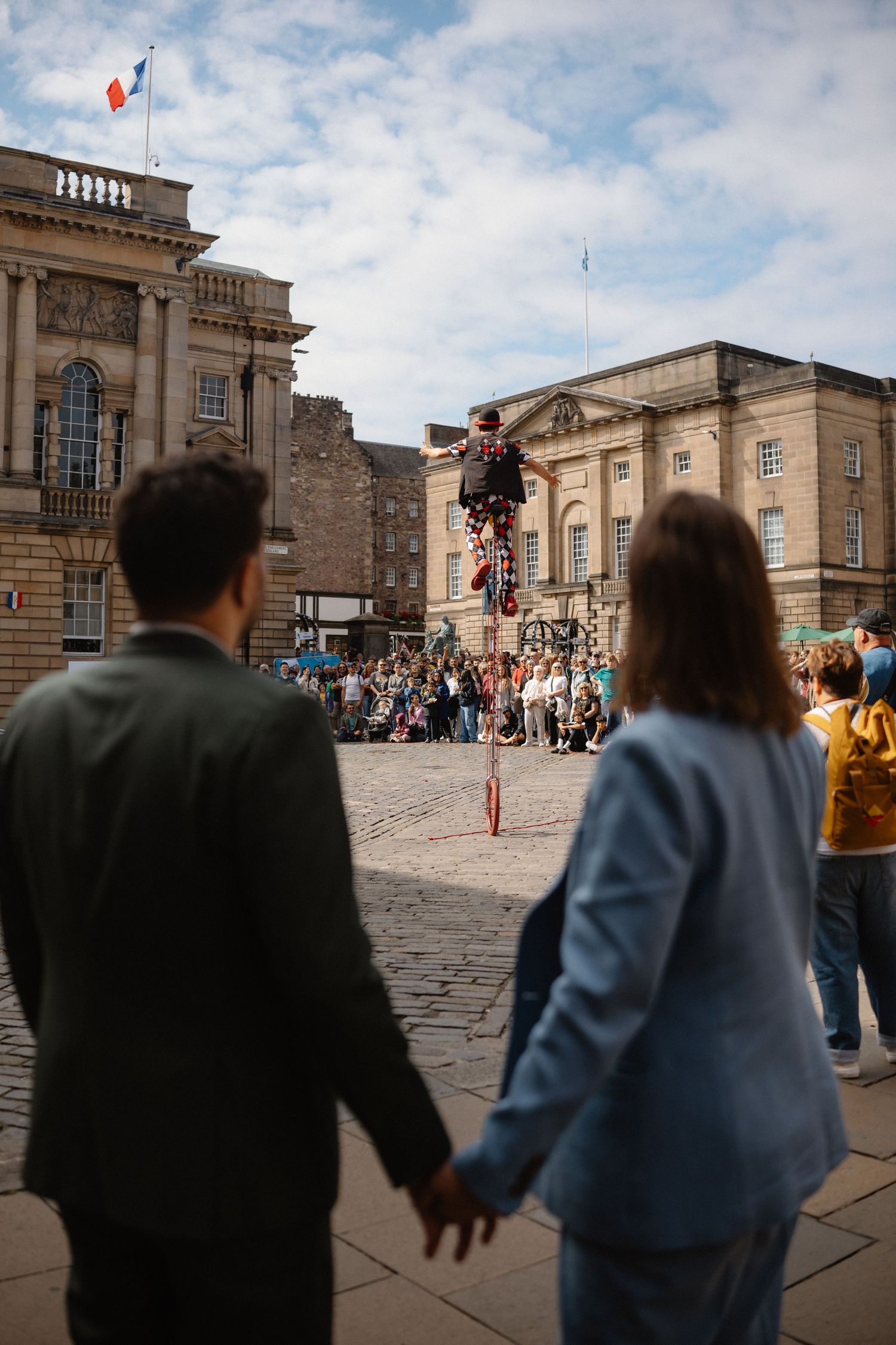 Street performers entertain tourists at Edinburgh Castle's historic courtyard on a cloudy afternoon.