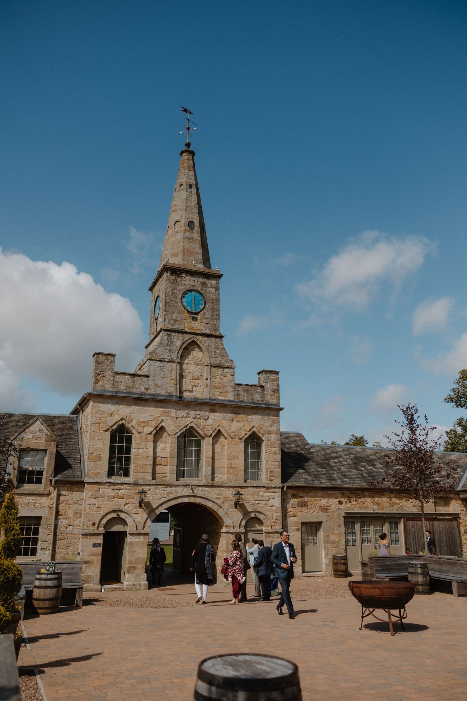 Historic stone building with clock tower and arched entrance at Culzean Castle in Scotland under blue skies.
