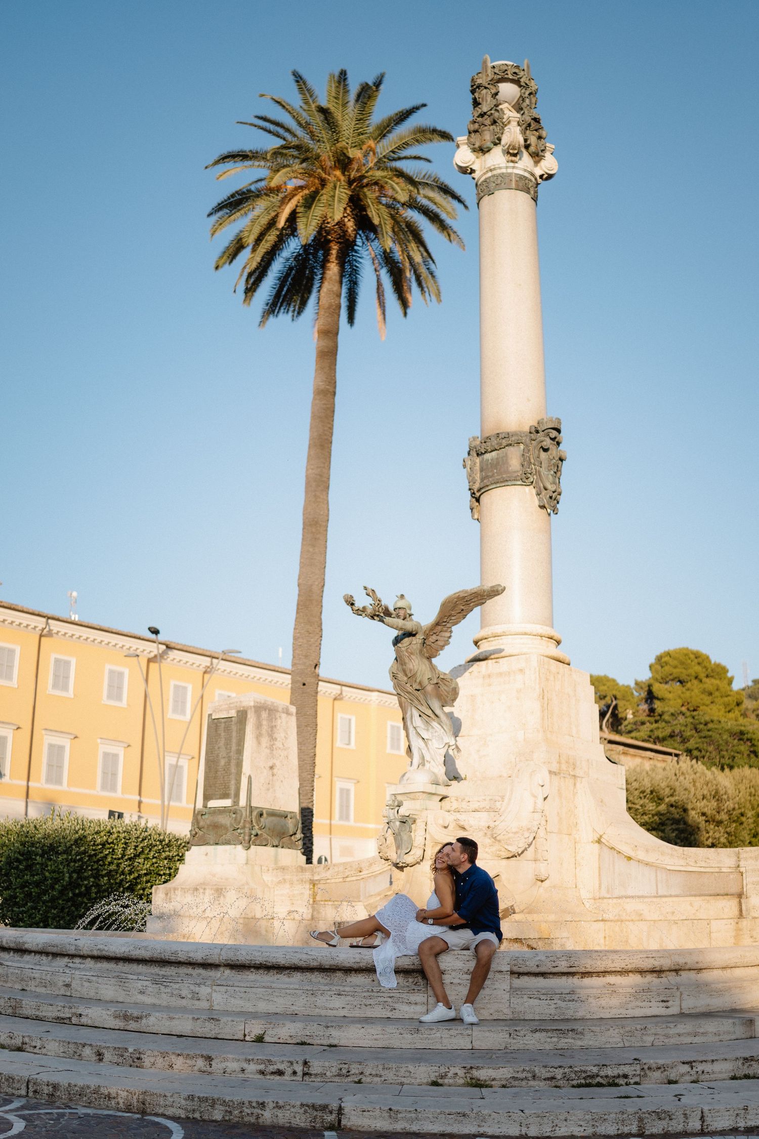 A romantic photoshoot on historic stone steps with palm trees and columns in Mediterranean setting.