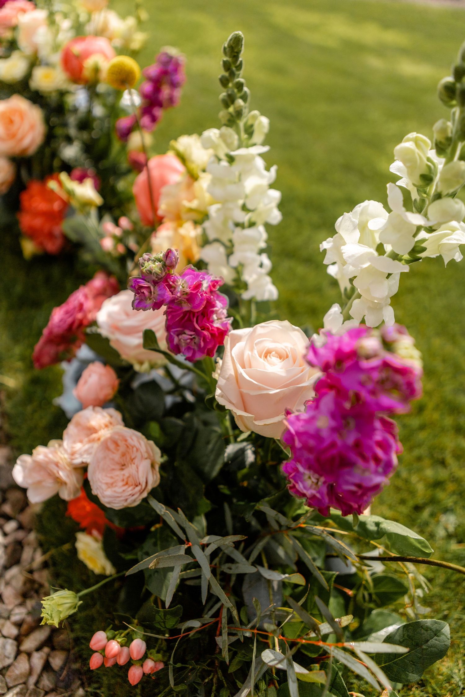 Colorful garden arrangement featuring pink roses, white snapdragons, and vibrant magenta flowers.