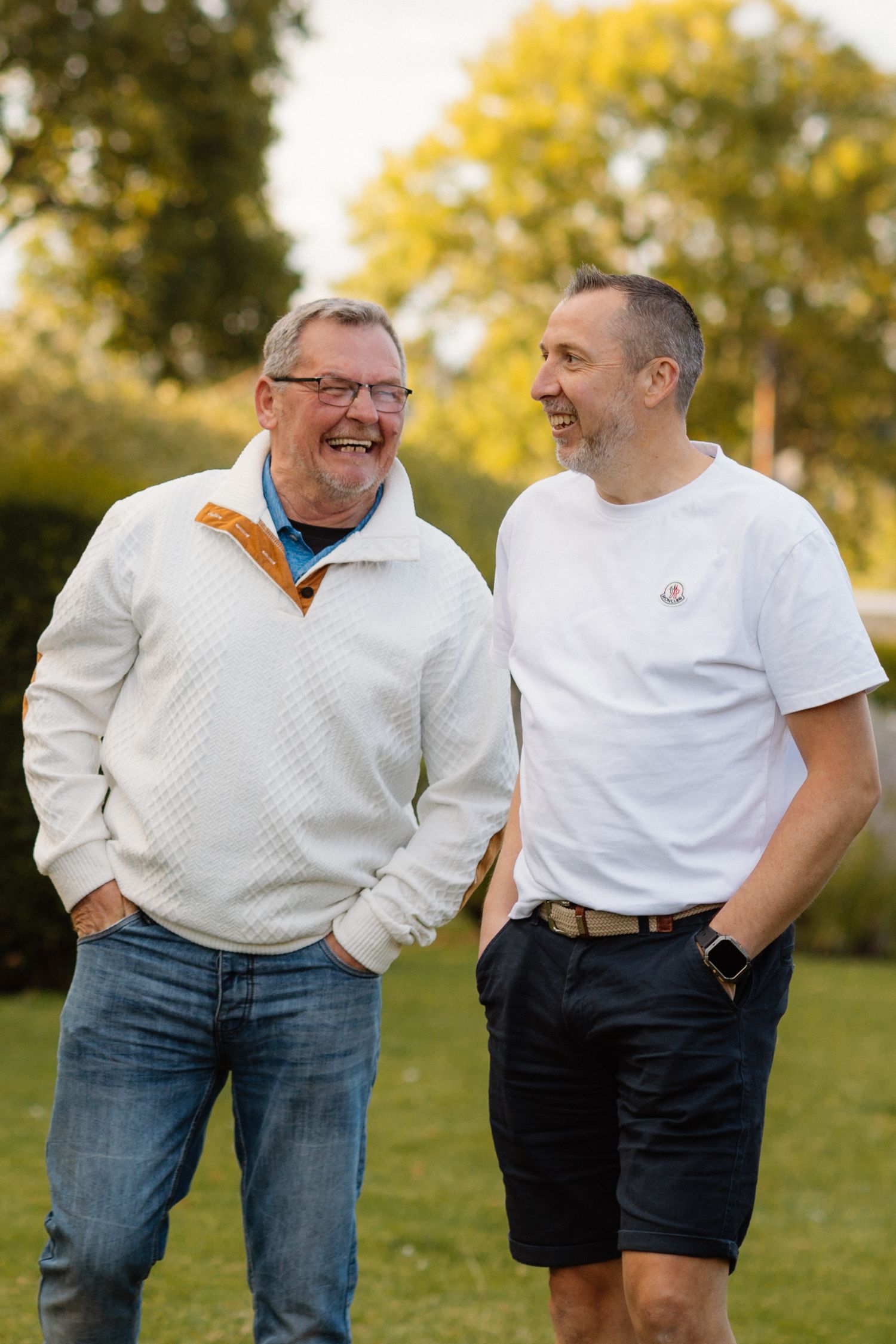 Two men sharing a laugh together outdoors in autumn setting.