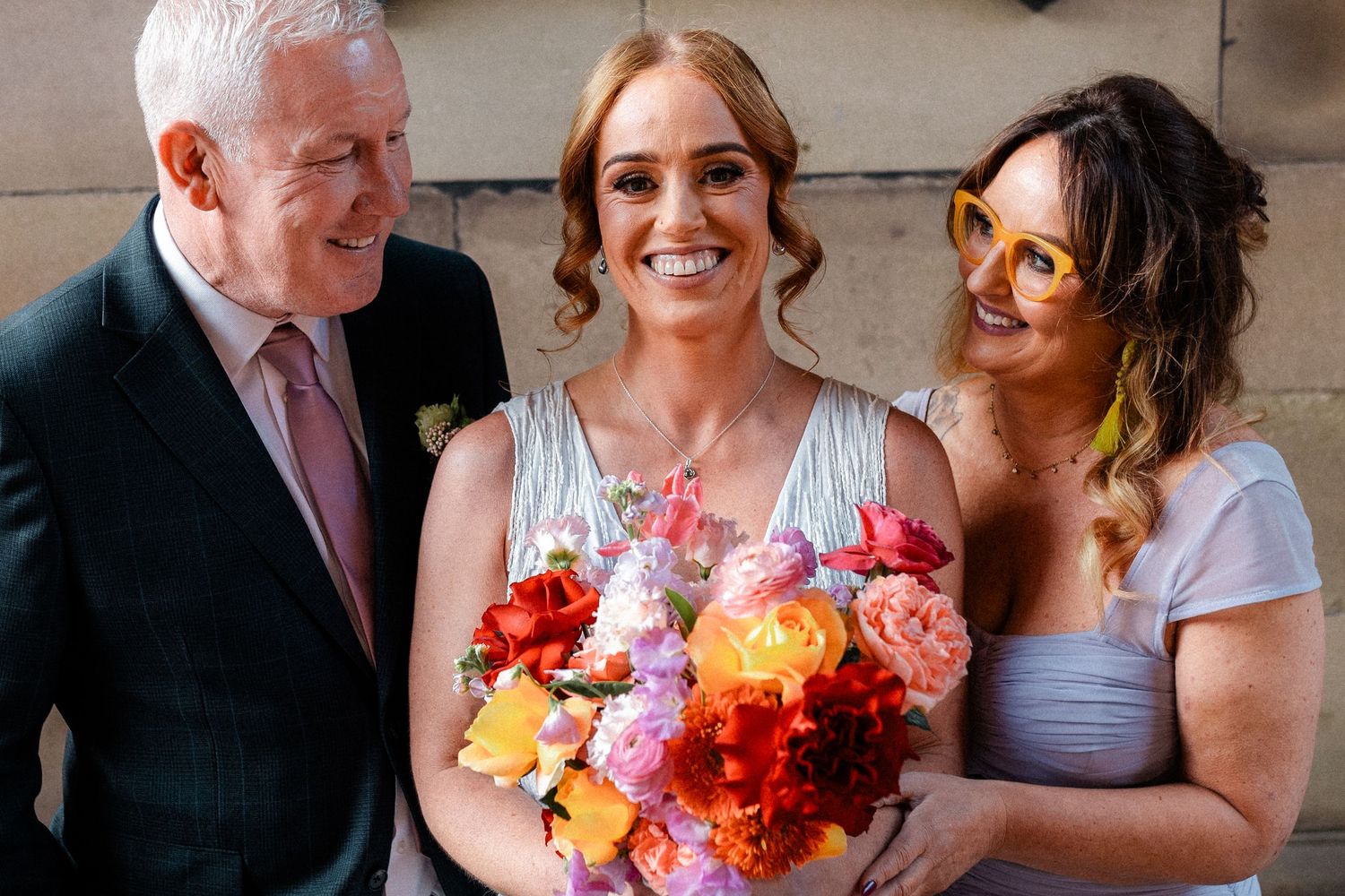 Wedding party members share joyful moments with colorful floral bouquets.