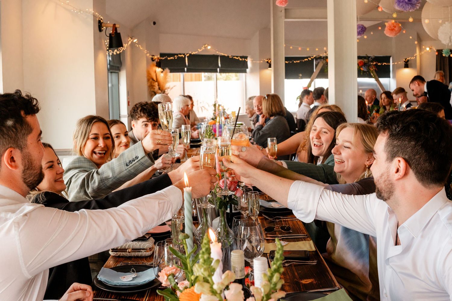 Wedding guests raising their arms in celebration during reception dinner party.