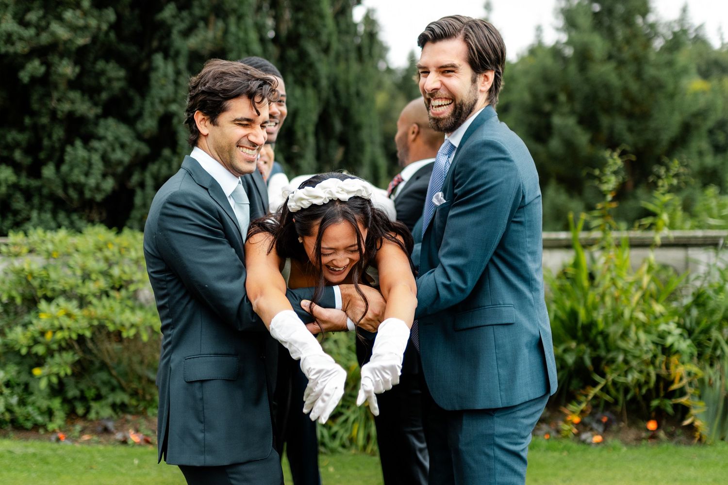 Candid moments of wedding party laughing and embracing outdoors in garden setting.