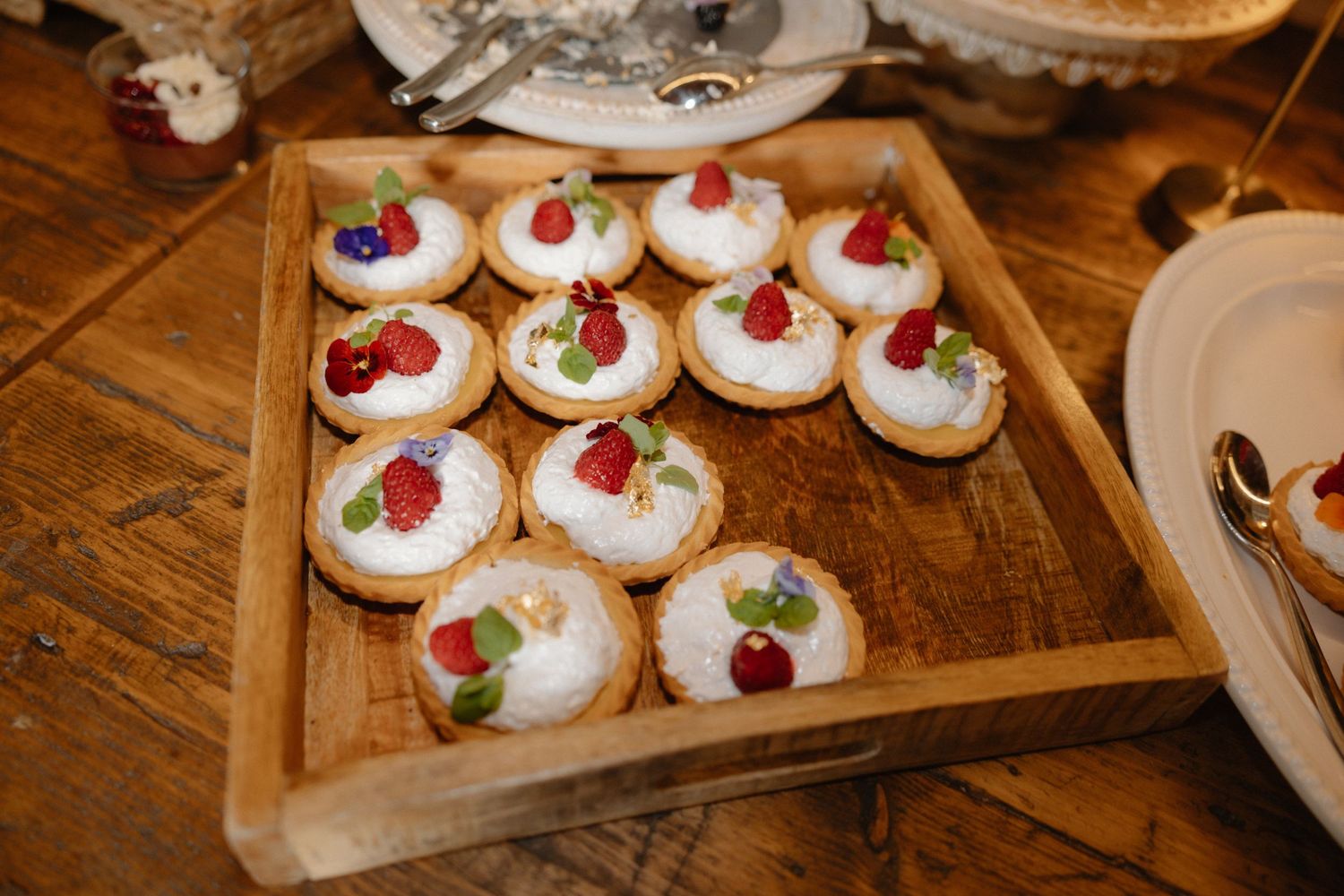 White frosted cookies decorated with red berries displayed on a wooden serving tray.