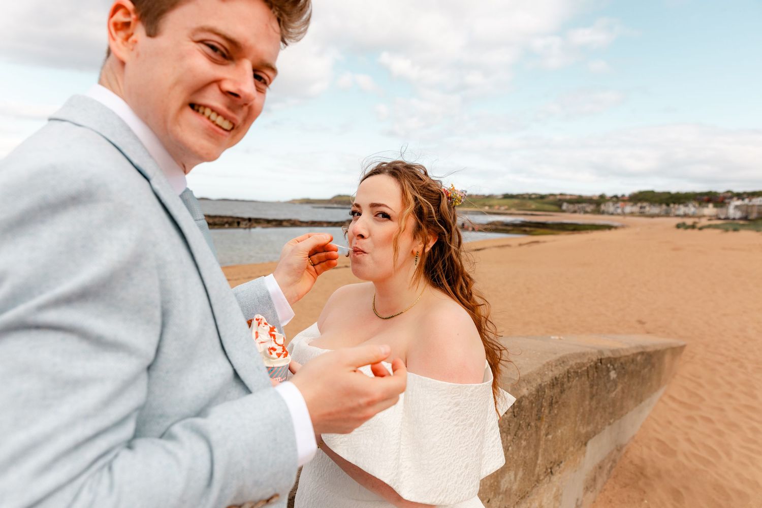 A couple shares a romantic moment together on a beach during a wedding photo session at sunset.