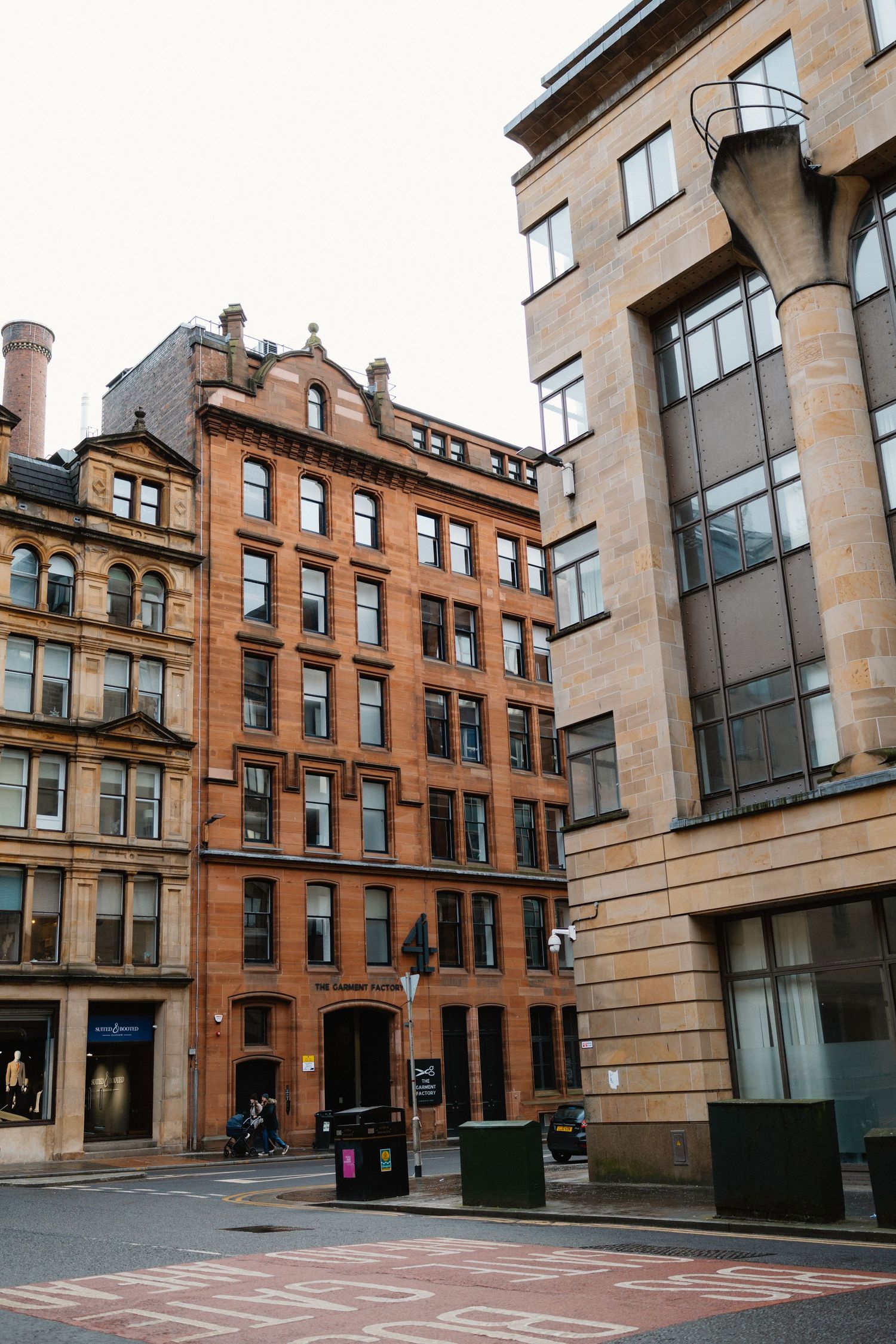 Historic red sandstone buildings line a quiet street corner in Glasgow city centre, Scotland.