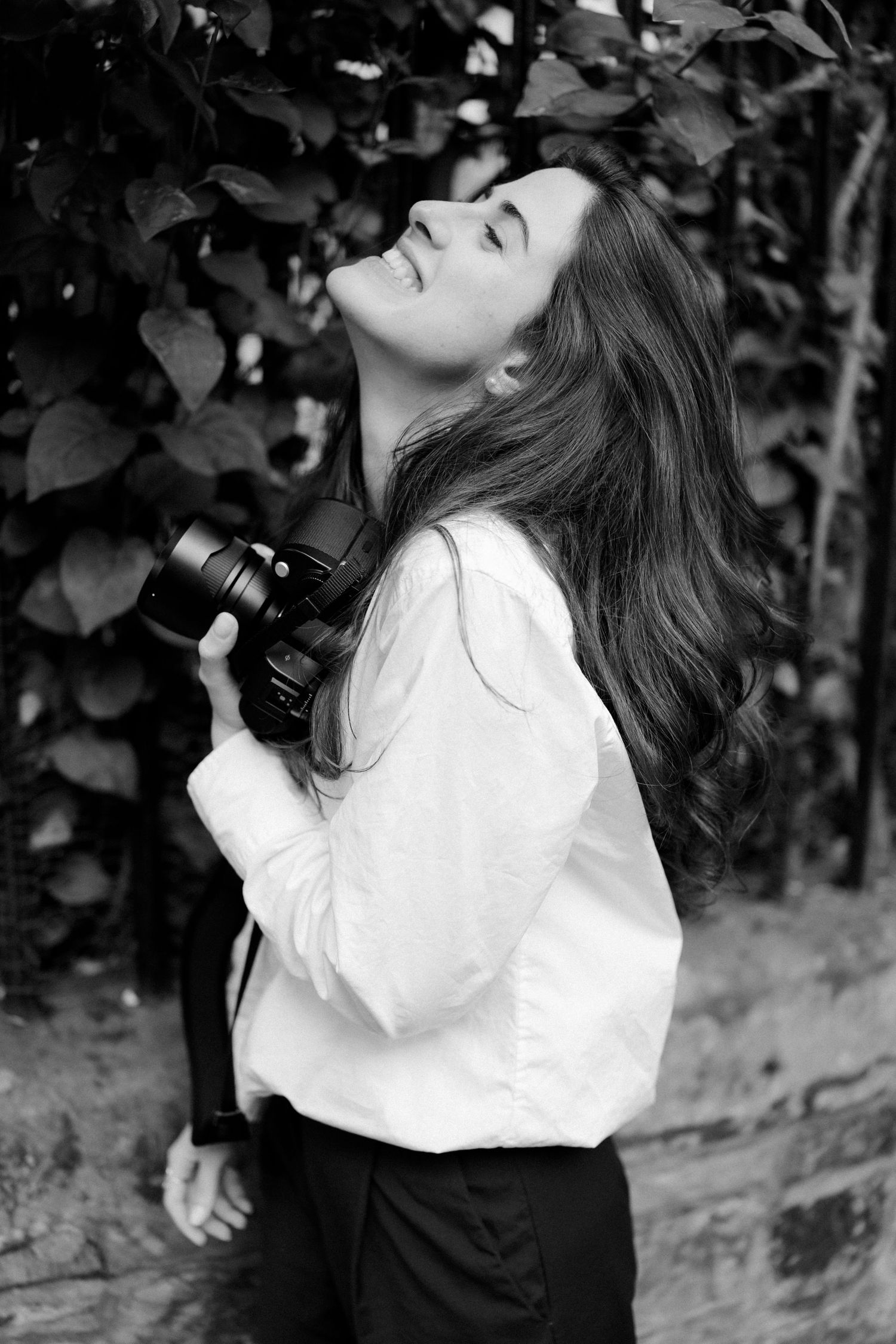 Artistic black and white portrait of person in white blouse looking upward.