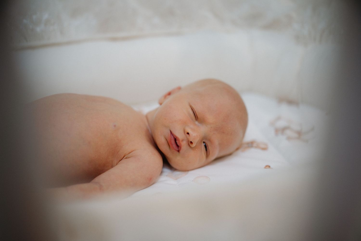Peaceful sleeping newborn baby wrapped in soft white blanket.