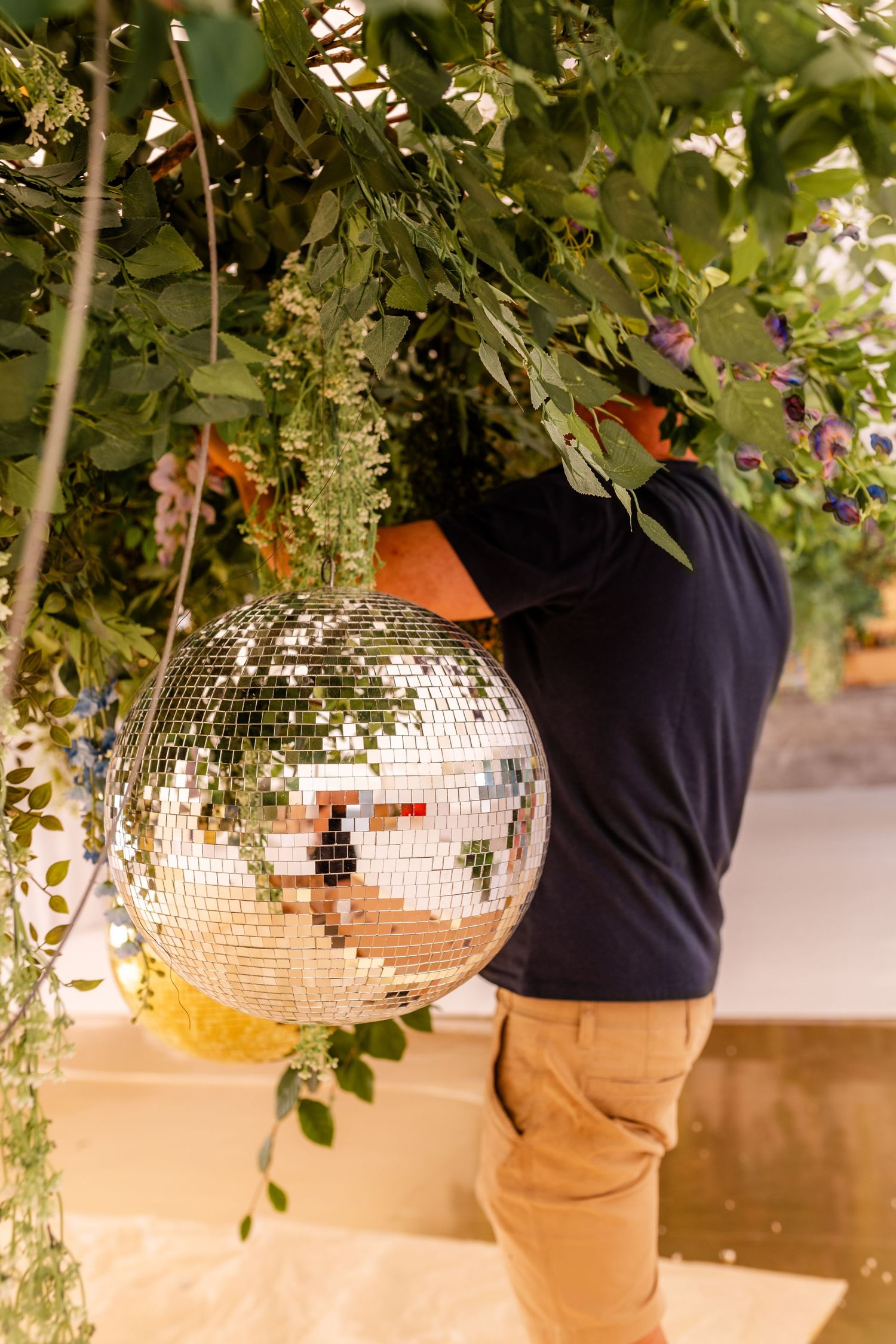 Disco balls hanging among green foliage create a magical garden party atmosphere.