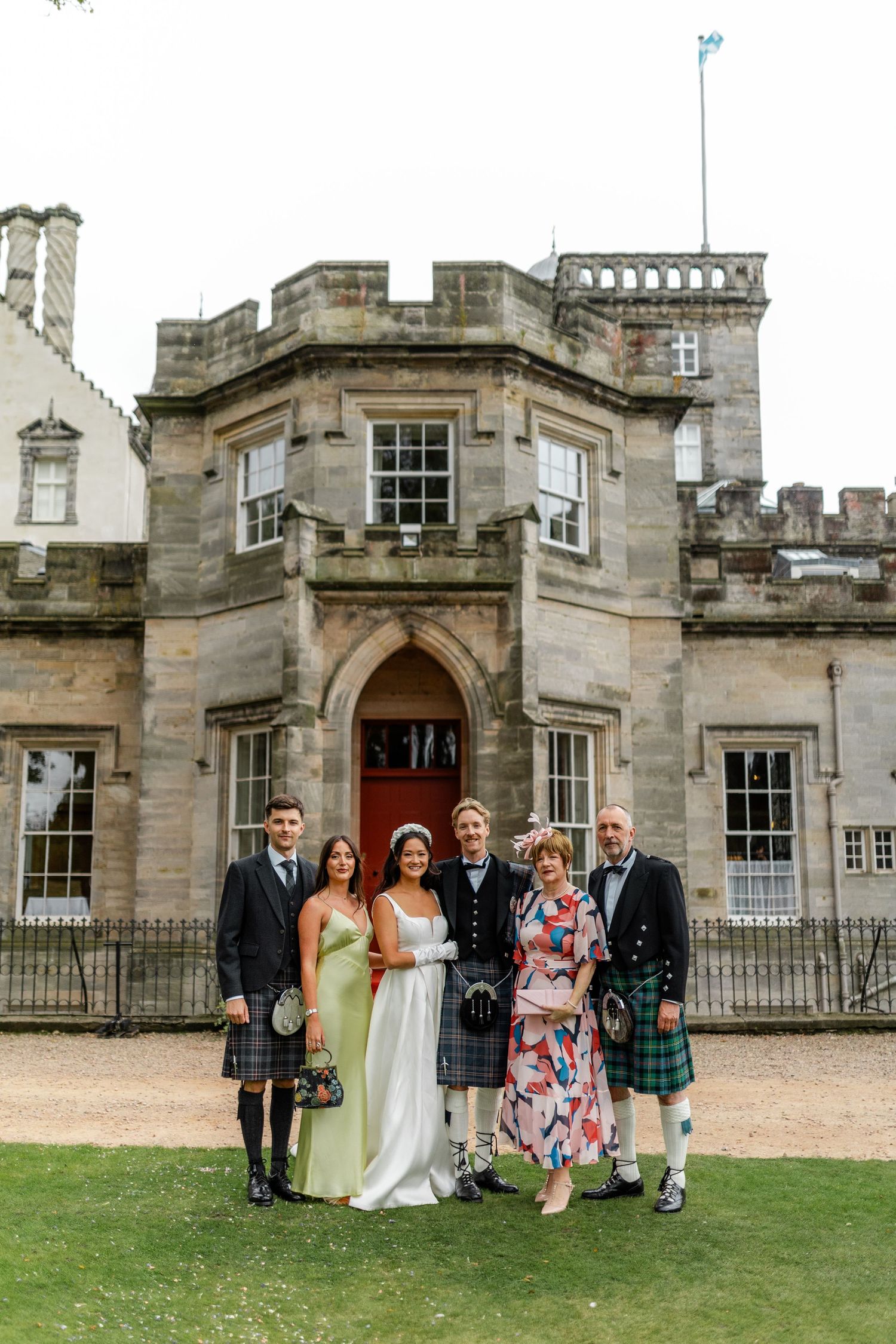 Family group photo outside historic Scottish castle during wedding celebration.