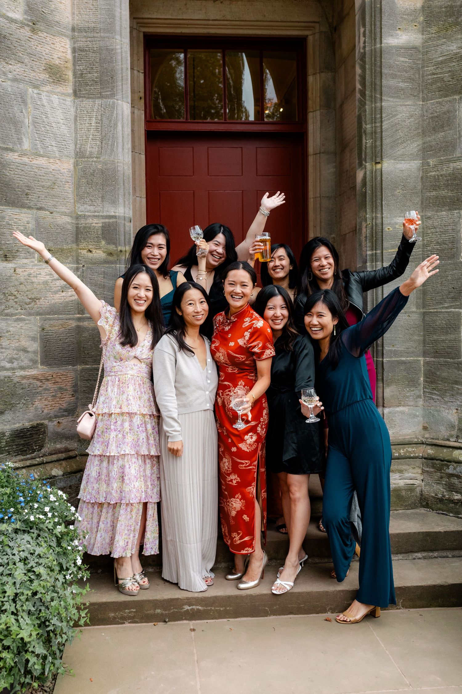 A celebratory group poses together outside a stone building entrance.
