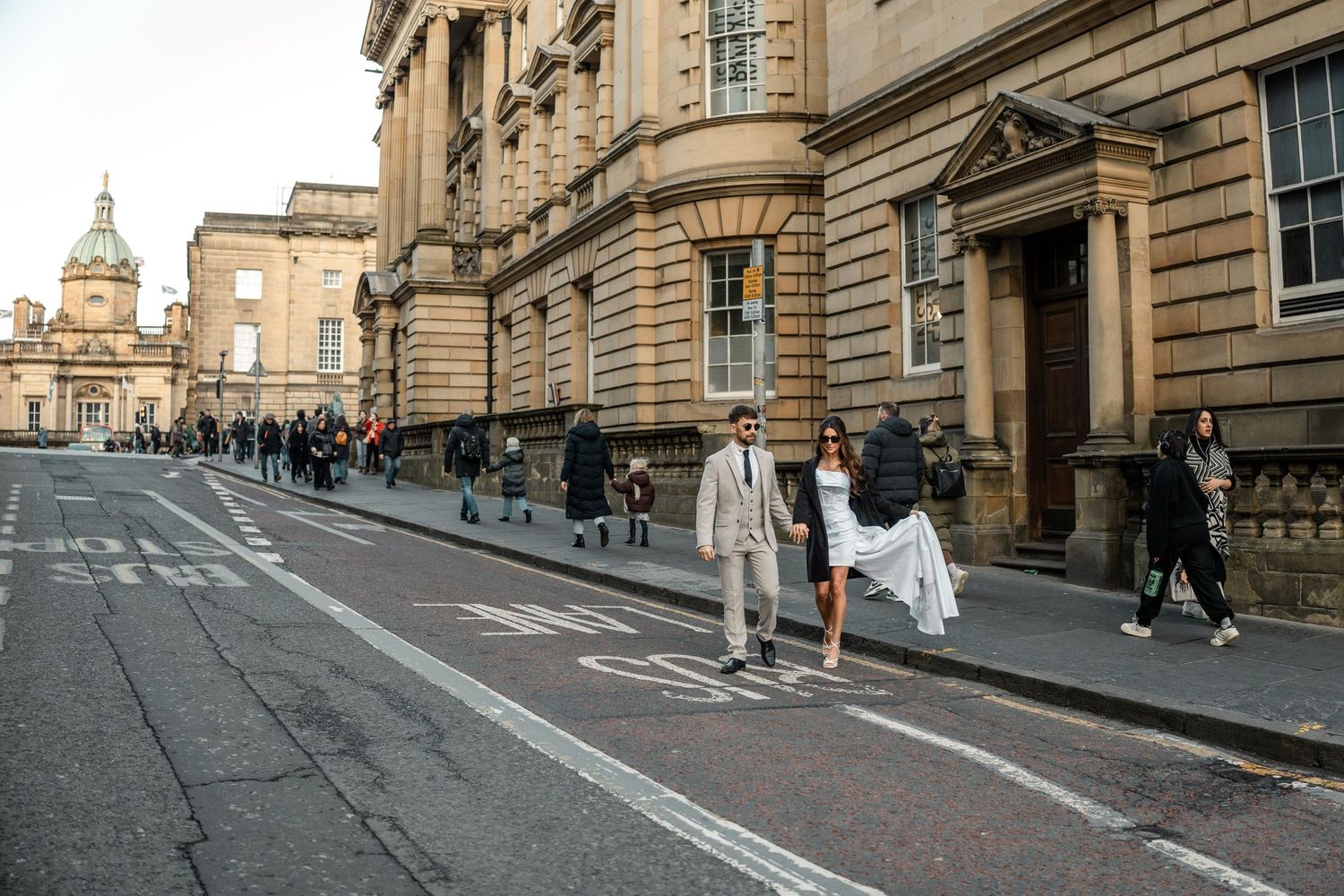 Urban street scene with historic stone buildings and pedestrians walking in Edinburgh.