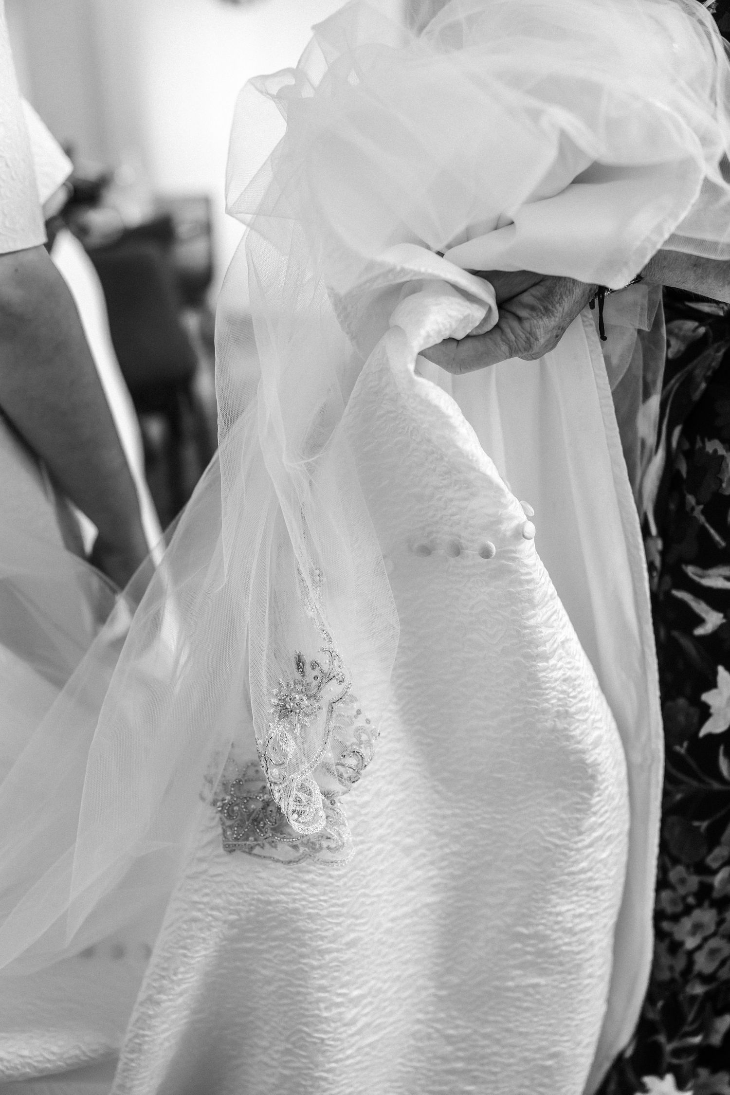 Close-up details of an elegant white wedding dress with intricate lace and flowing veil.