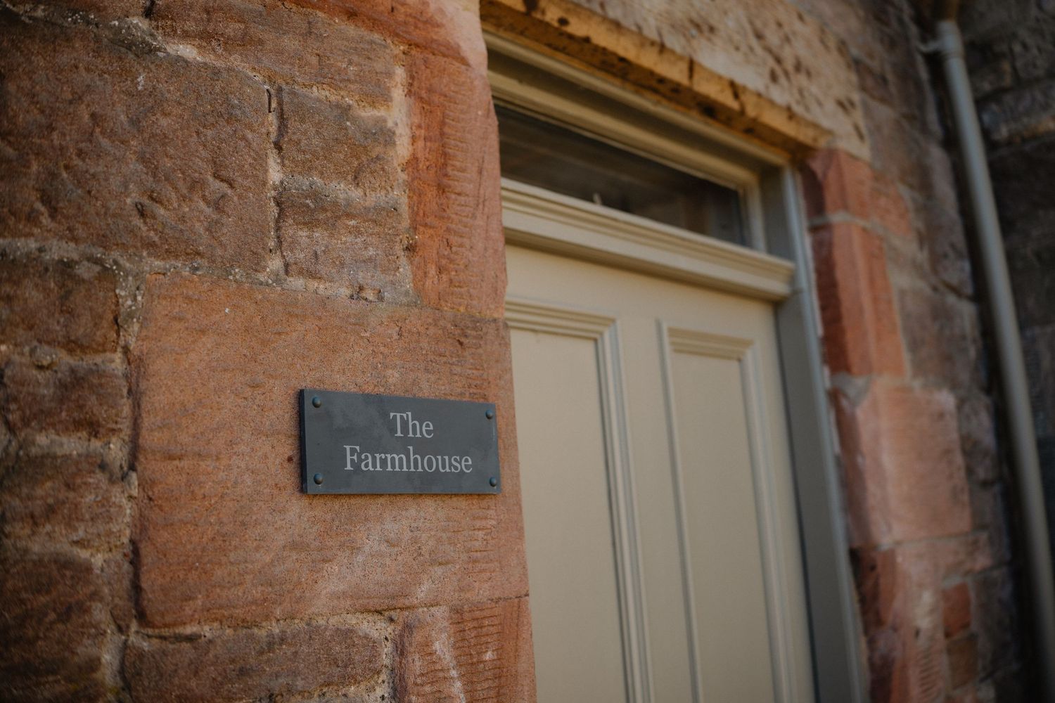 Close-up view of weathered red brick wall with cream-colored window trim and a partial view of a building sign.