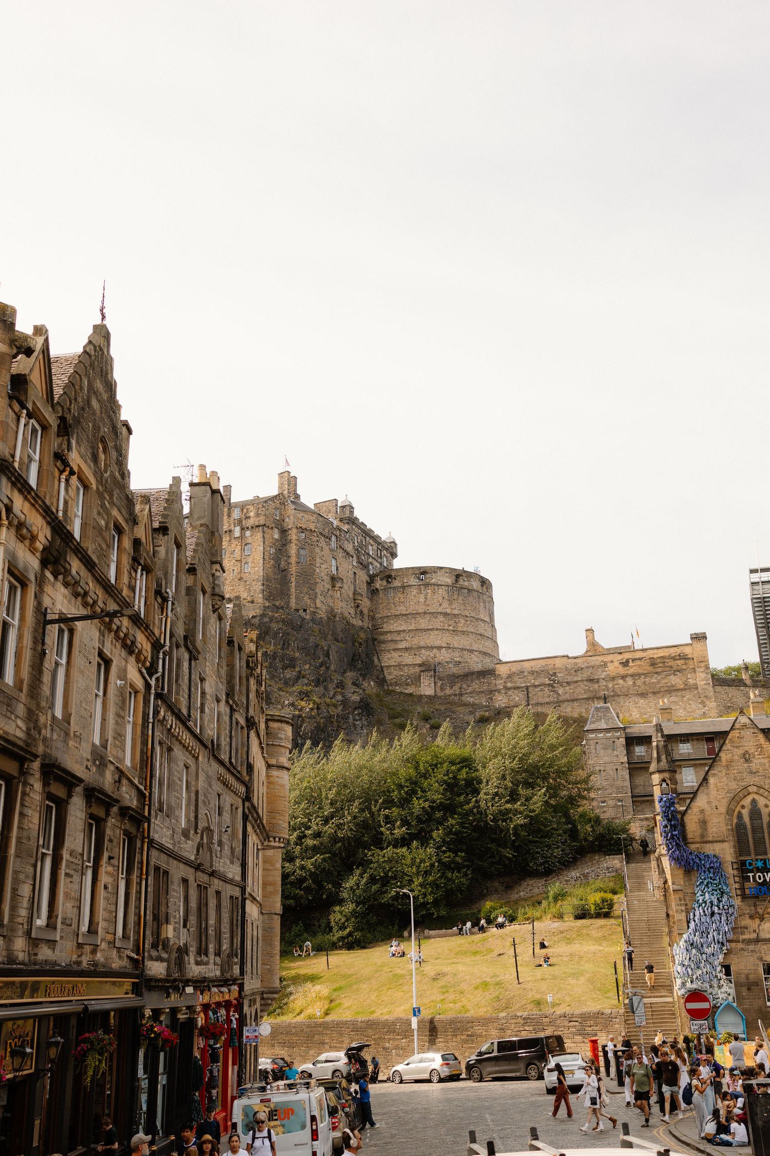 Edinburgh Castle perched on volcanic rock overlooking busy Grassmarket street below.