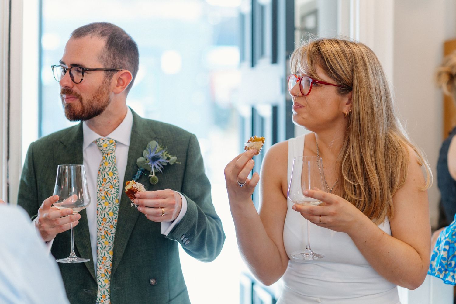 People enjoying drinks and conversation in a bright windowed room.