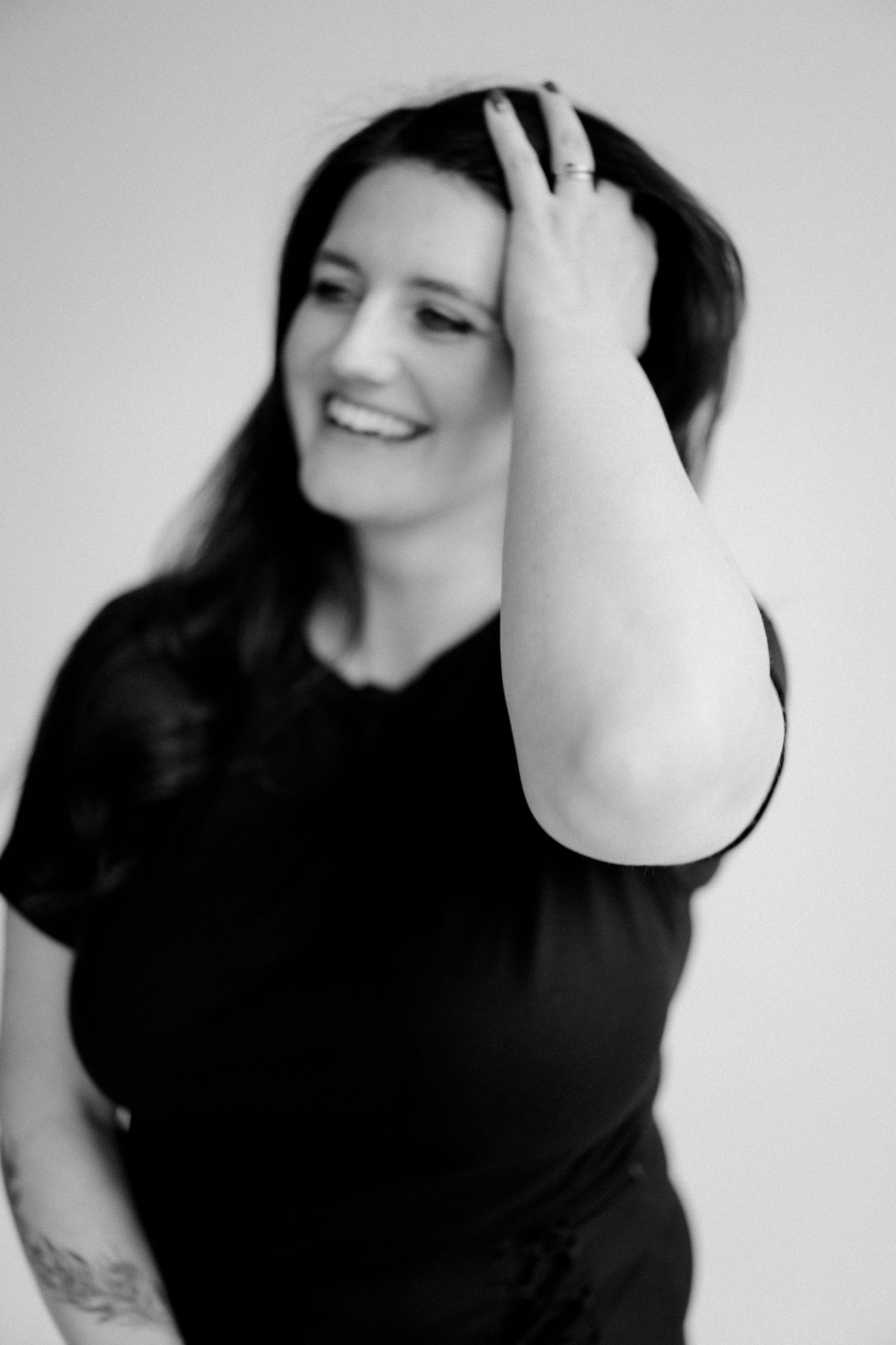 Black and white portrait of person running hand through hair while smiling.
