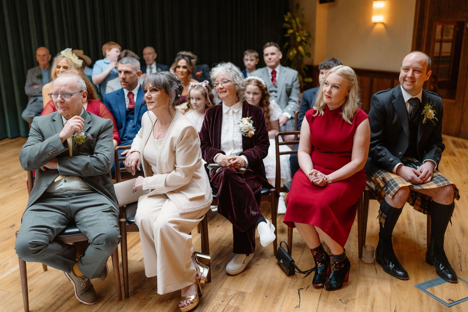 Wedding guests seated in chairs during a ceremony, including a bride in white and guests in formal attire.