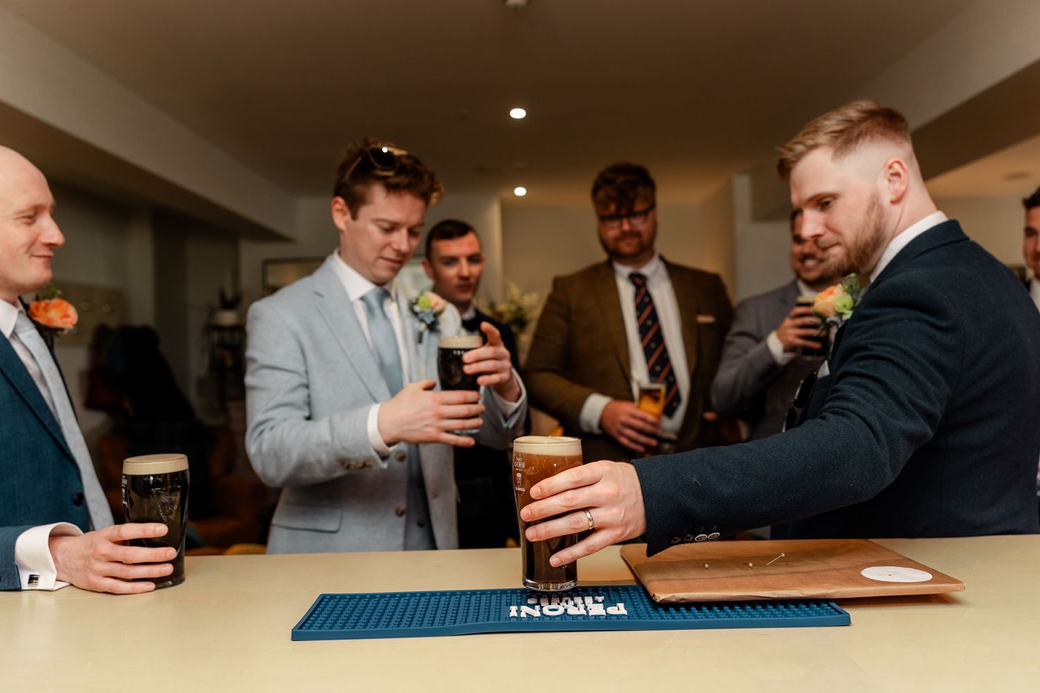 Groomsmen gathered around a bar counter raising glasses in celebration.